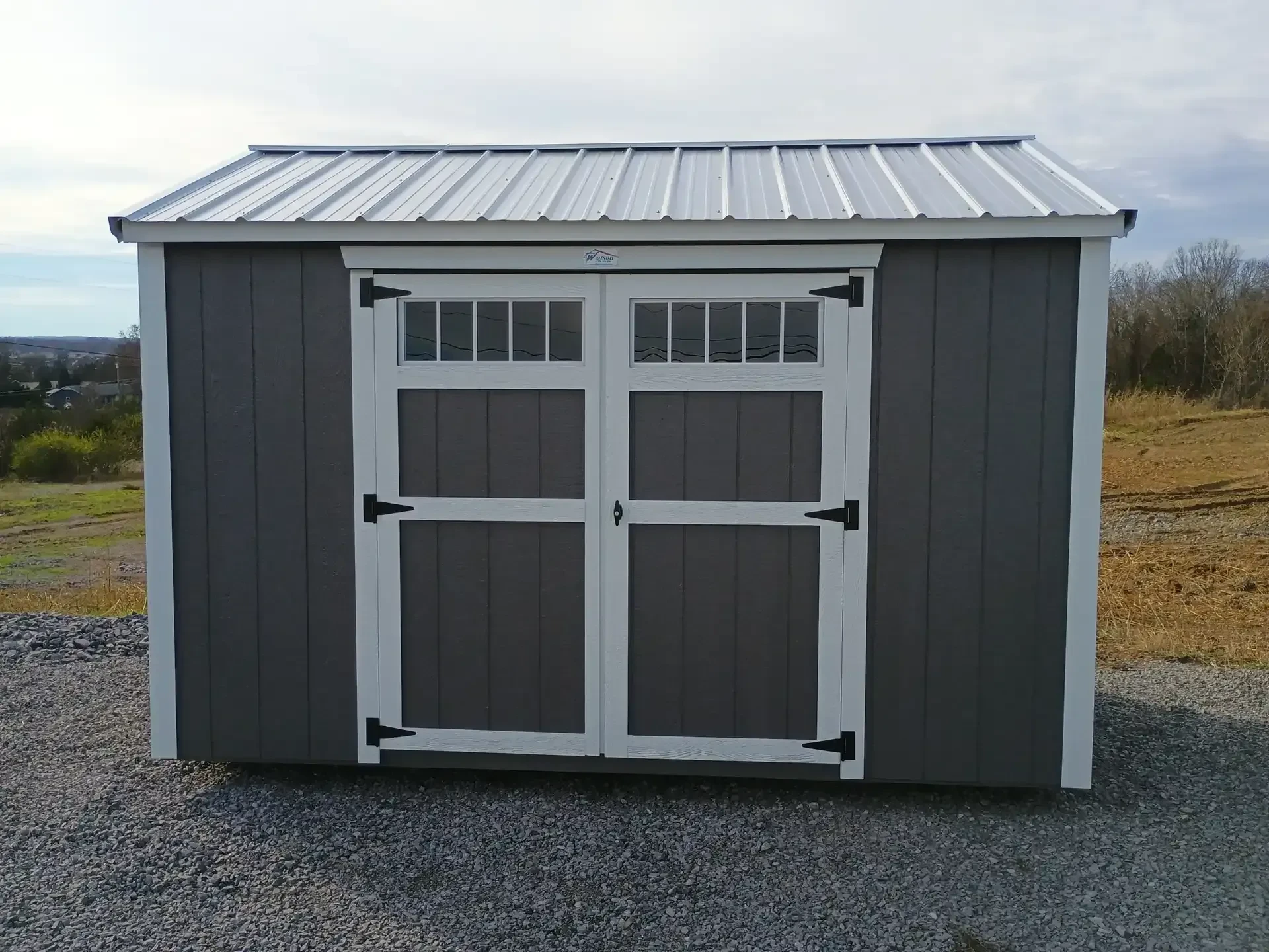 a charcoal colored garden shed with transom windows on the double doors