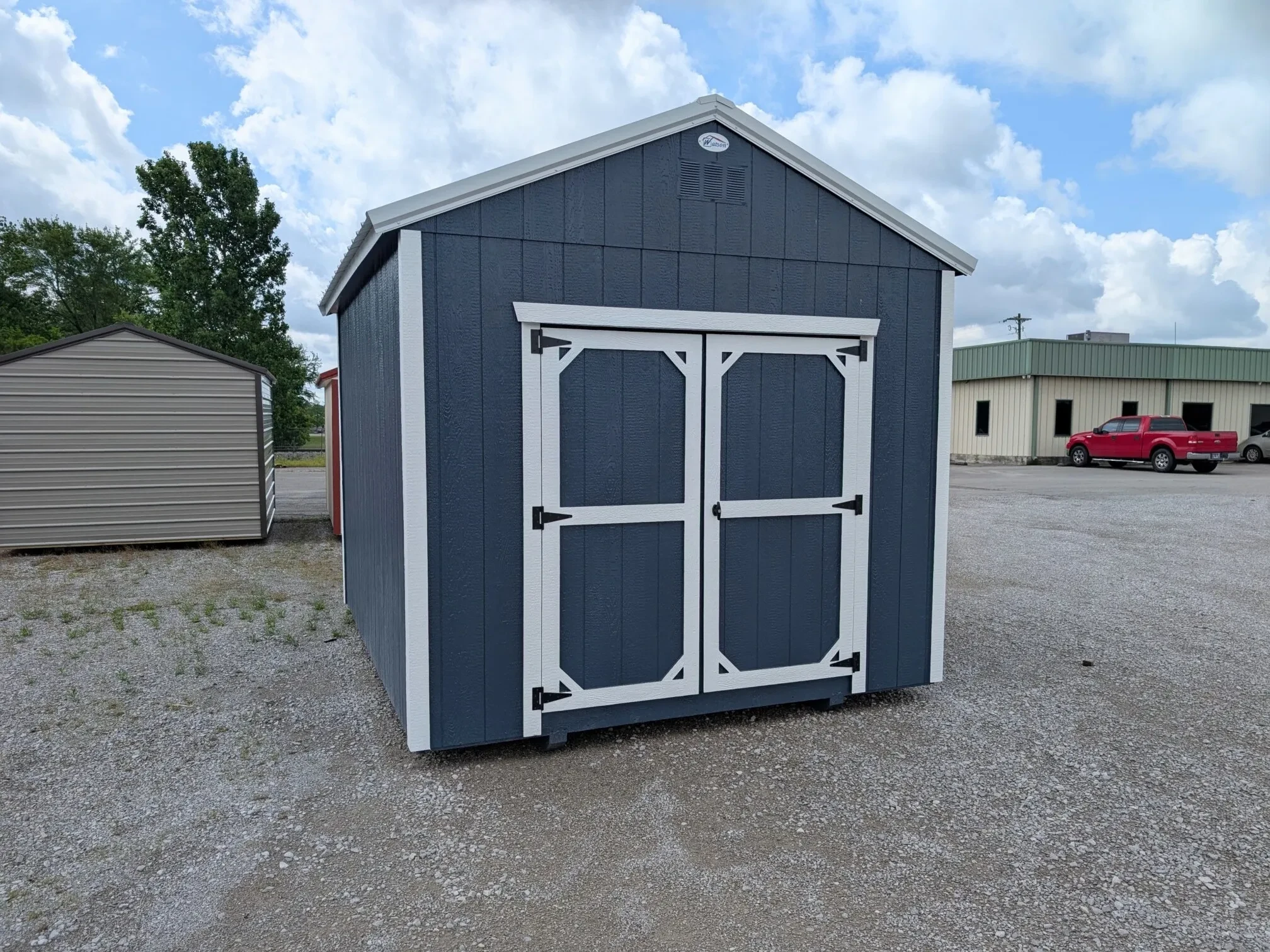 a wood shed painted blue with double doors and white trim