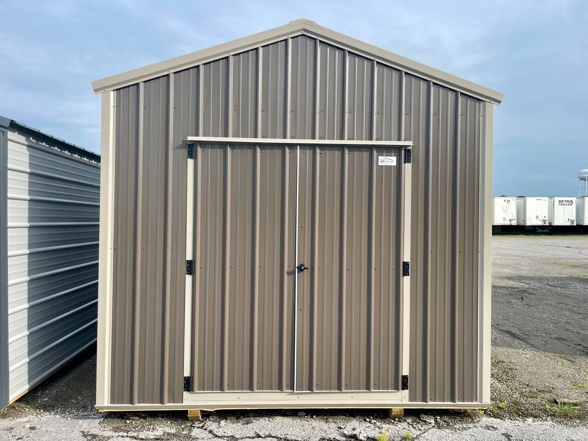 a metal utility shed that is bronze colored with clay colored trim