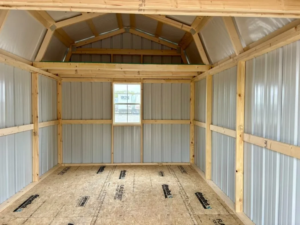 inside a metal lofted barn with a window along the back wall and a loft