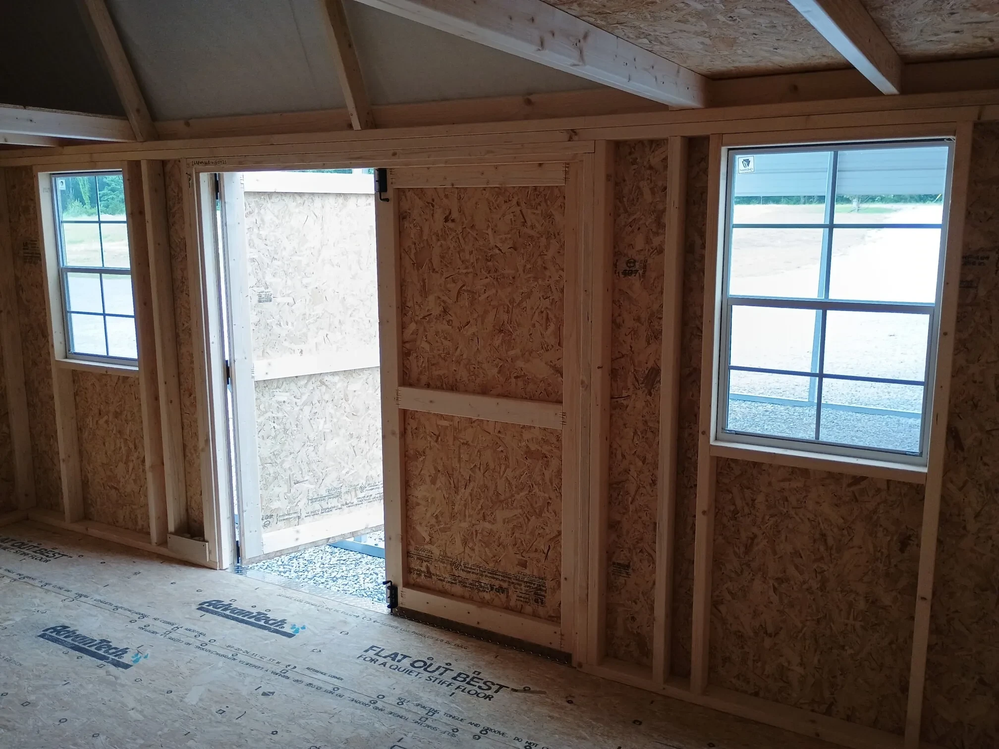 inside a lofted barn looking through the double doors that have windows on each side