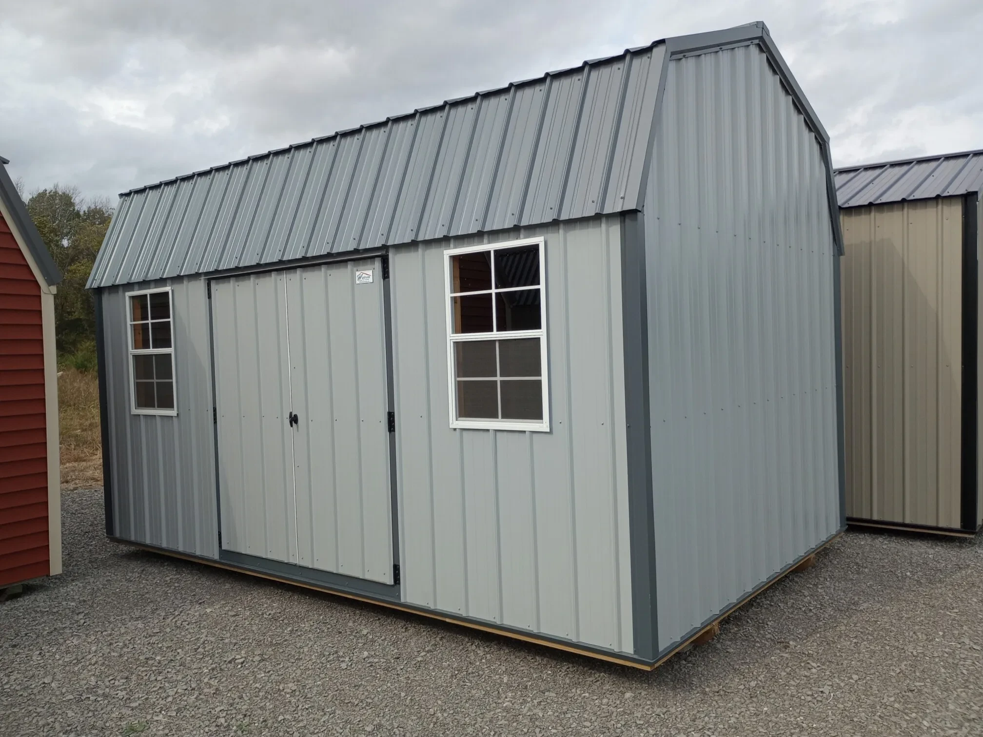a gray metal side lofted barn with double doors and two windows