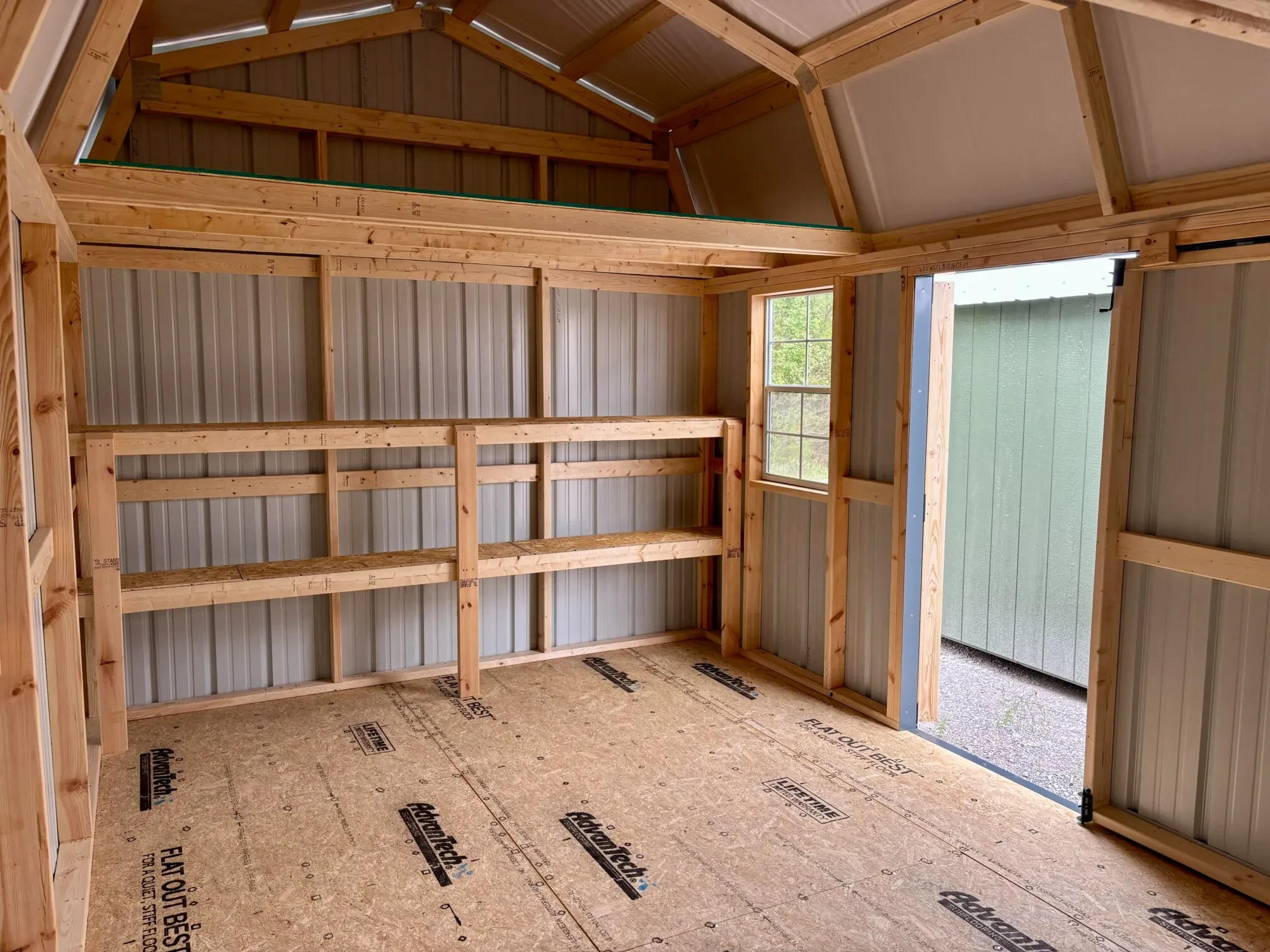 inside a metal lofted barn with double shelves, a loft, and the double doors open
