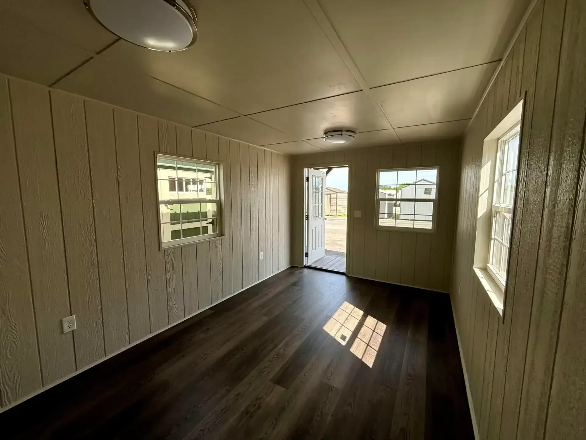 inside a fully finished out cabin looking at the walk-in door which is open, and it has multiple vinyl insulated windows