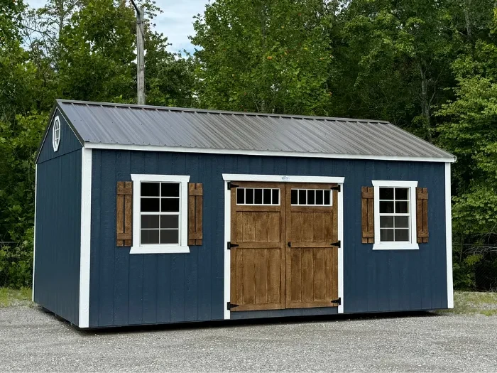 a pretty dark blue garden shed with brown double doors with transom windows and two standard windows with brown shutters