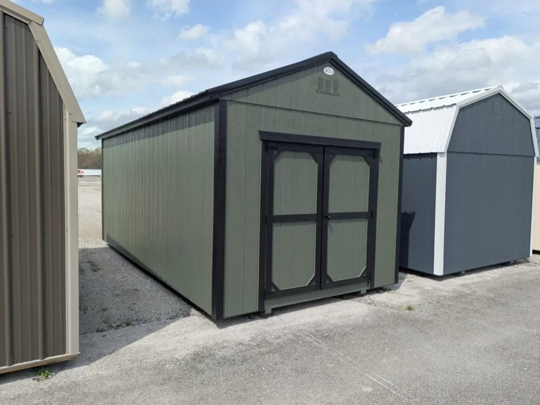 a green shed with black trim and a black roof and double doors