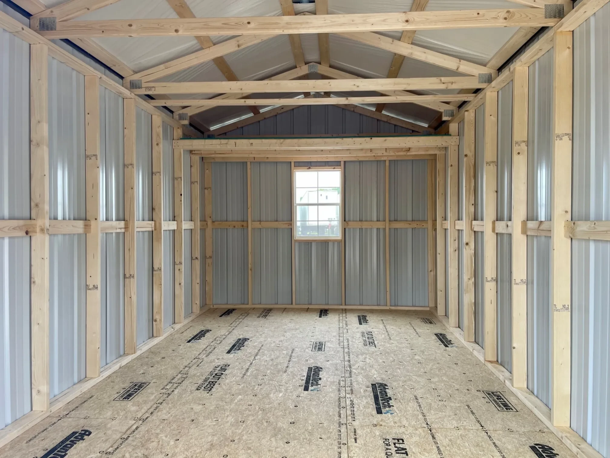 inside a metal shed with a loft and a window in the middle of the back wall