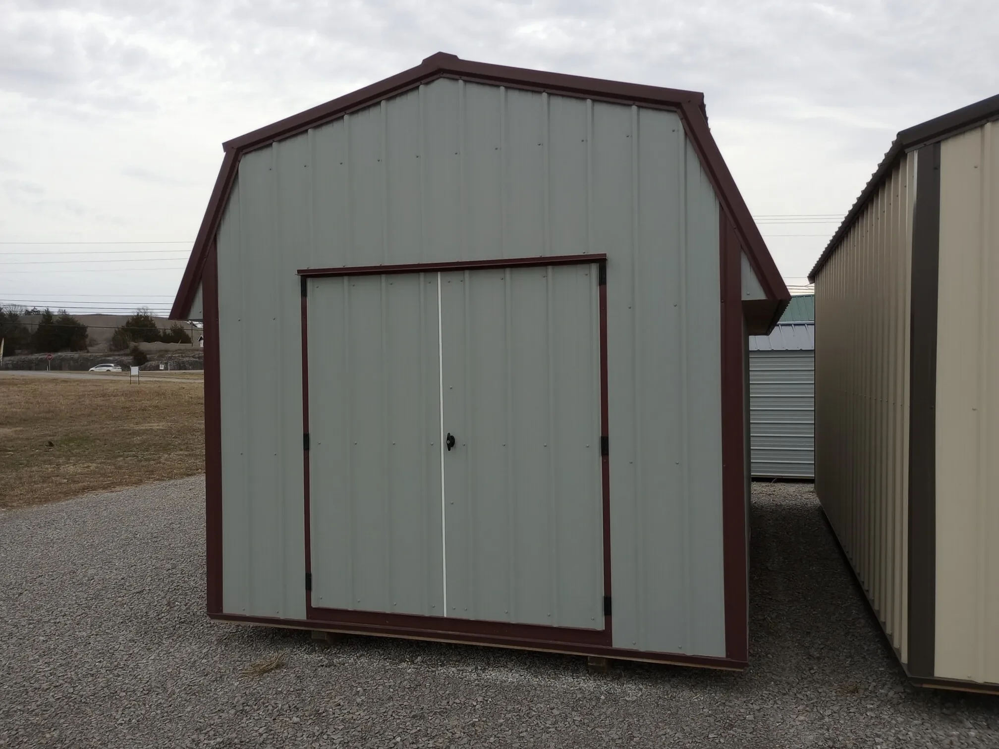 a light gray metal lofted barn with burgundy trim and double doors