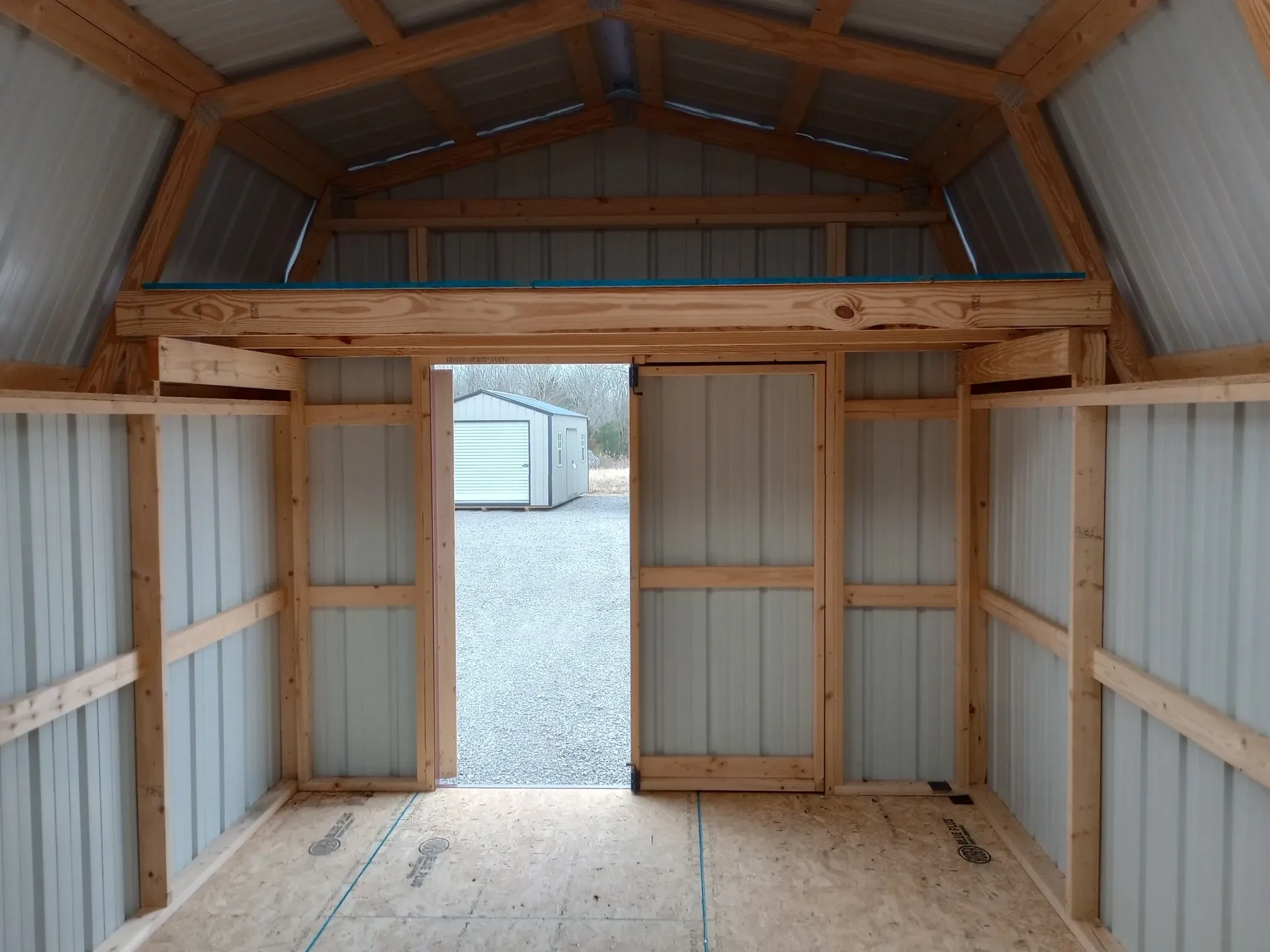 inside a metal lofted barn looking through the open double doors that has a loft above it
