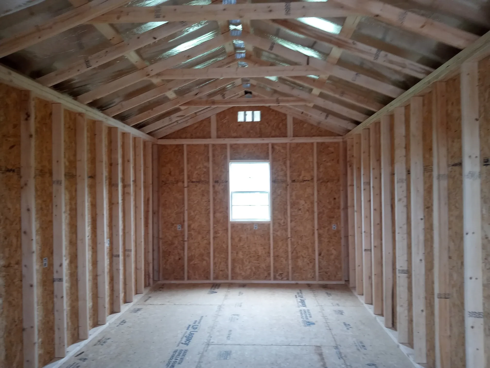 inside a wood utility shed with a window in the back wall