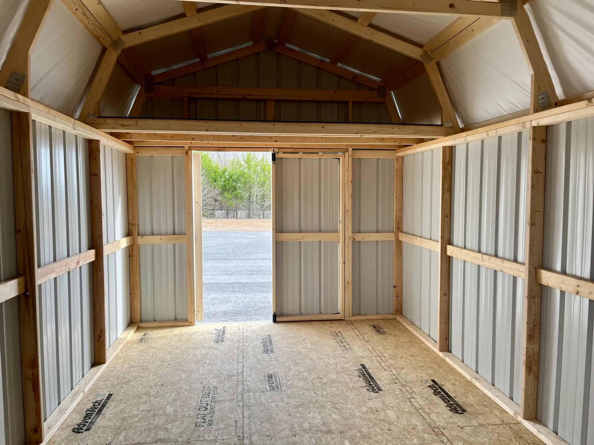 the interior of a metal lofted barn with a loft above the open double doors