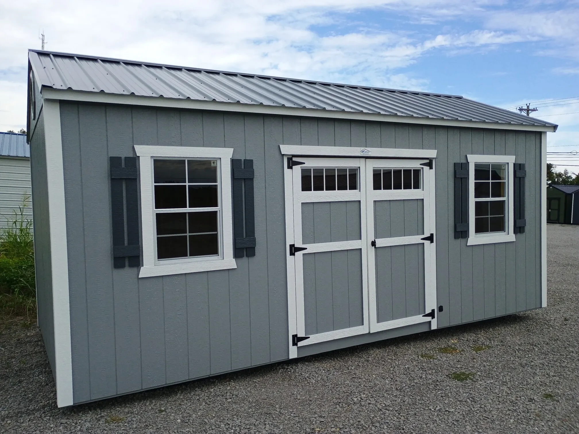 a garden shed with transom windows on the double doors and windows on each side