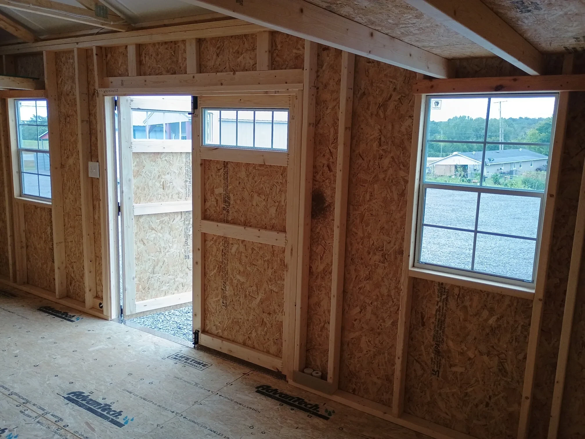 looking out through the double doors with transom windows from the inside of a wood shed