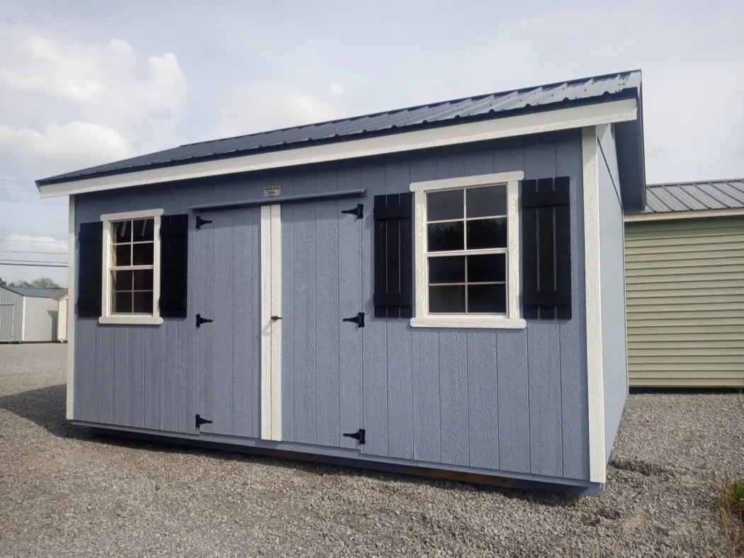 a blue garden shed with two windows with shutters and double doors and a roof overhang