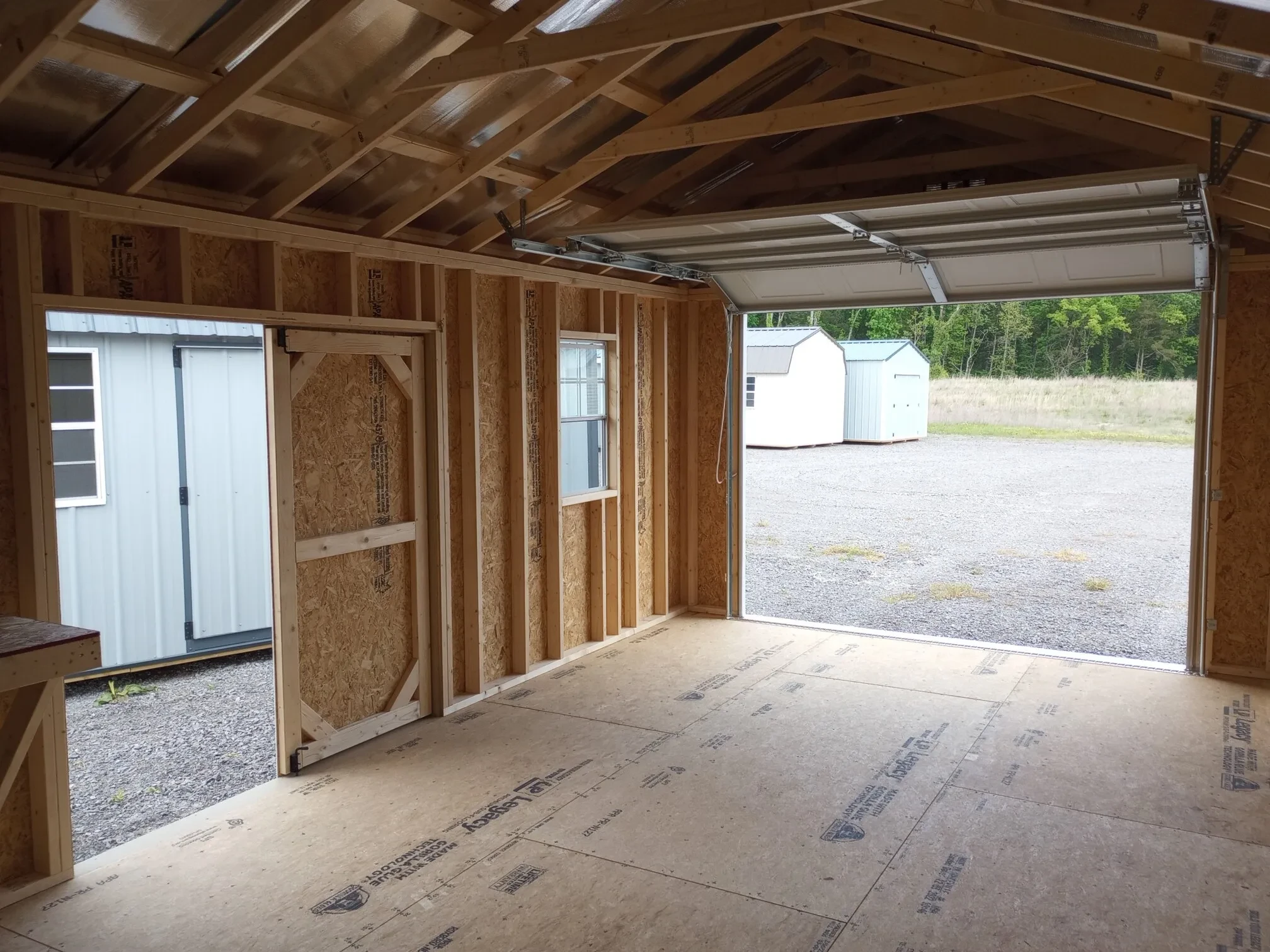 looking through the overhead garage door that is open from the inside of a garage shed