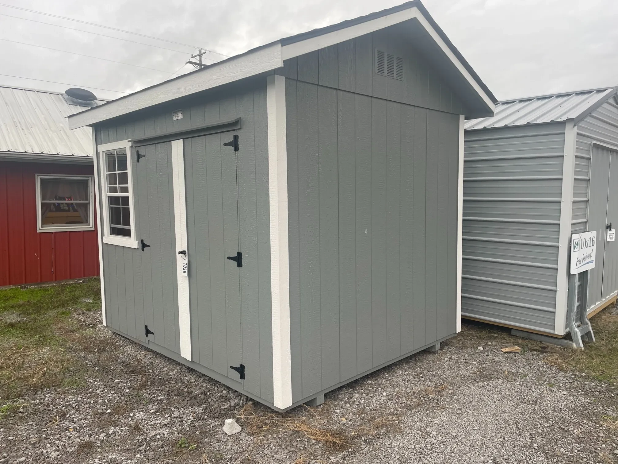 a small gr shed with shingles on the roof and a window on the wall
