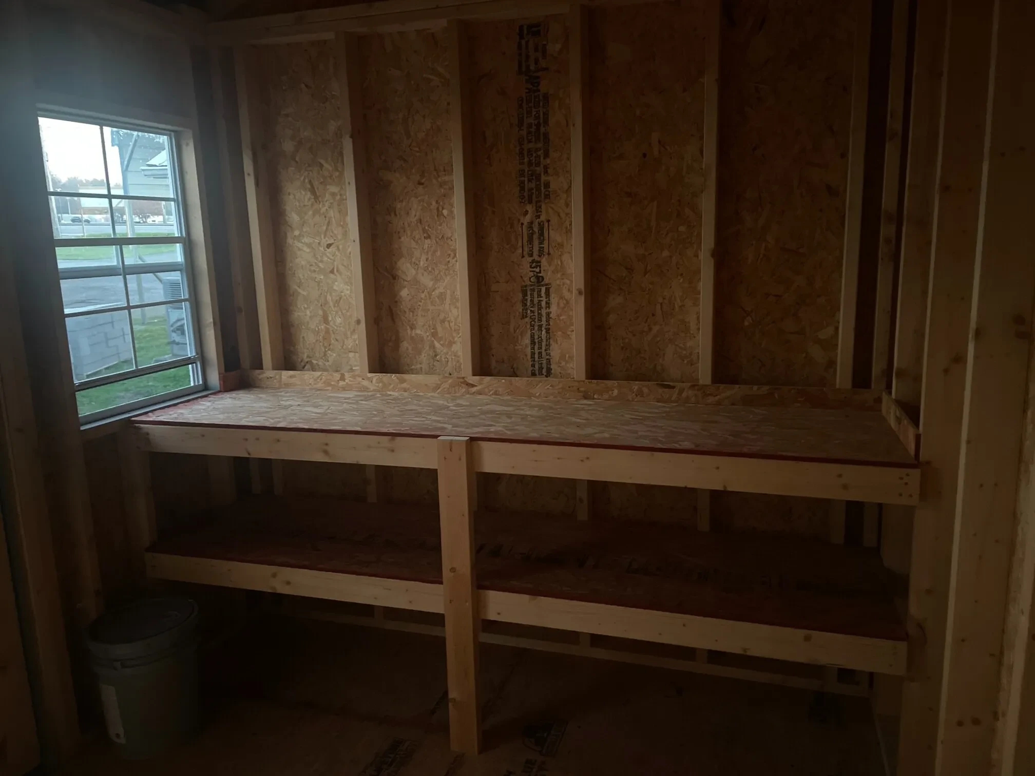 double shelves next to a window inside a small wood shed