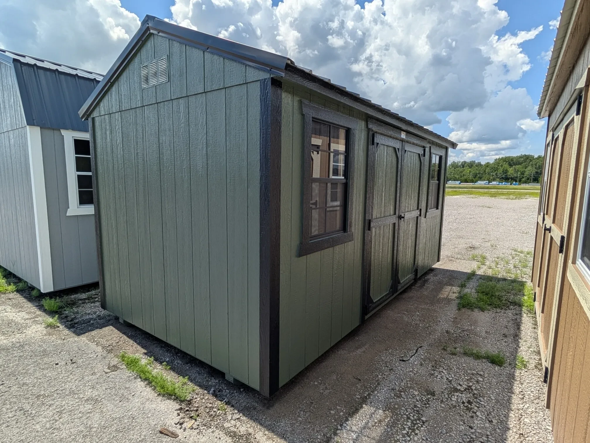 a green garden shed with black trim and it has a window on each side of the double doors