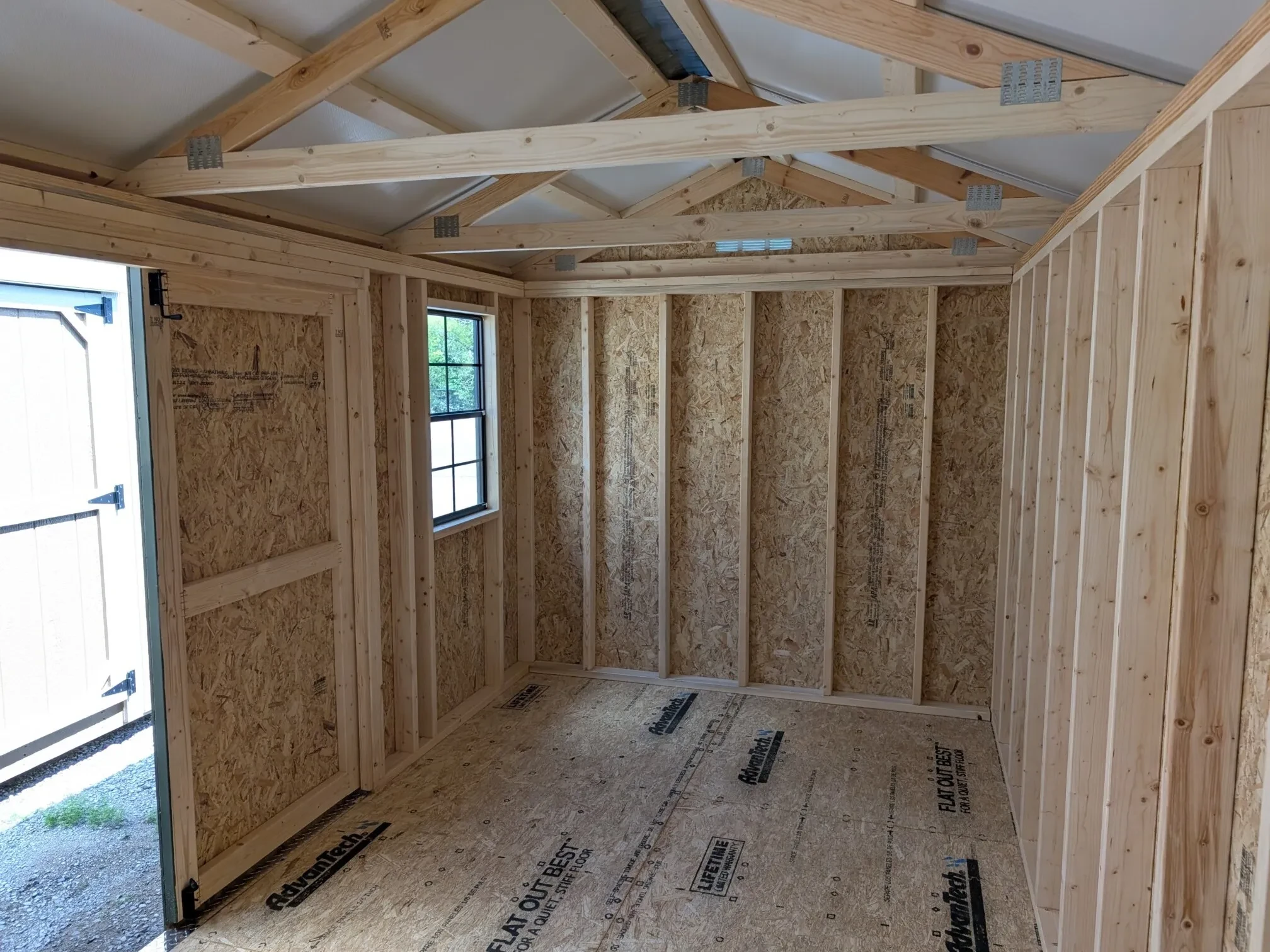 the left interior of a wood garden shed which has a window on the front wall