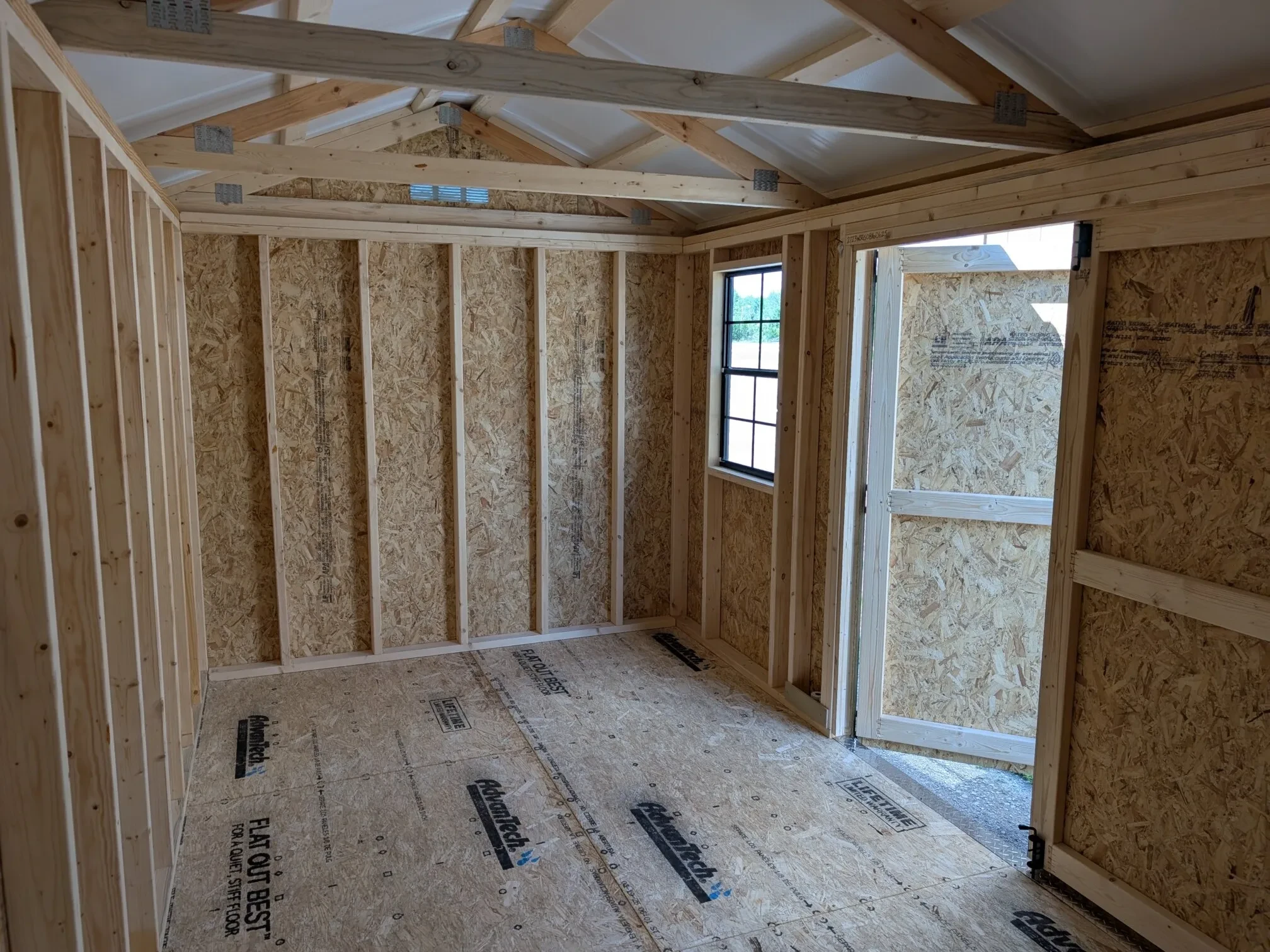 the right interior of a wood garden shed which has a window on the front wall