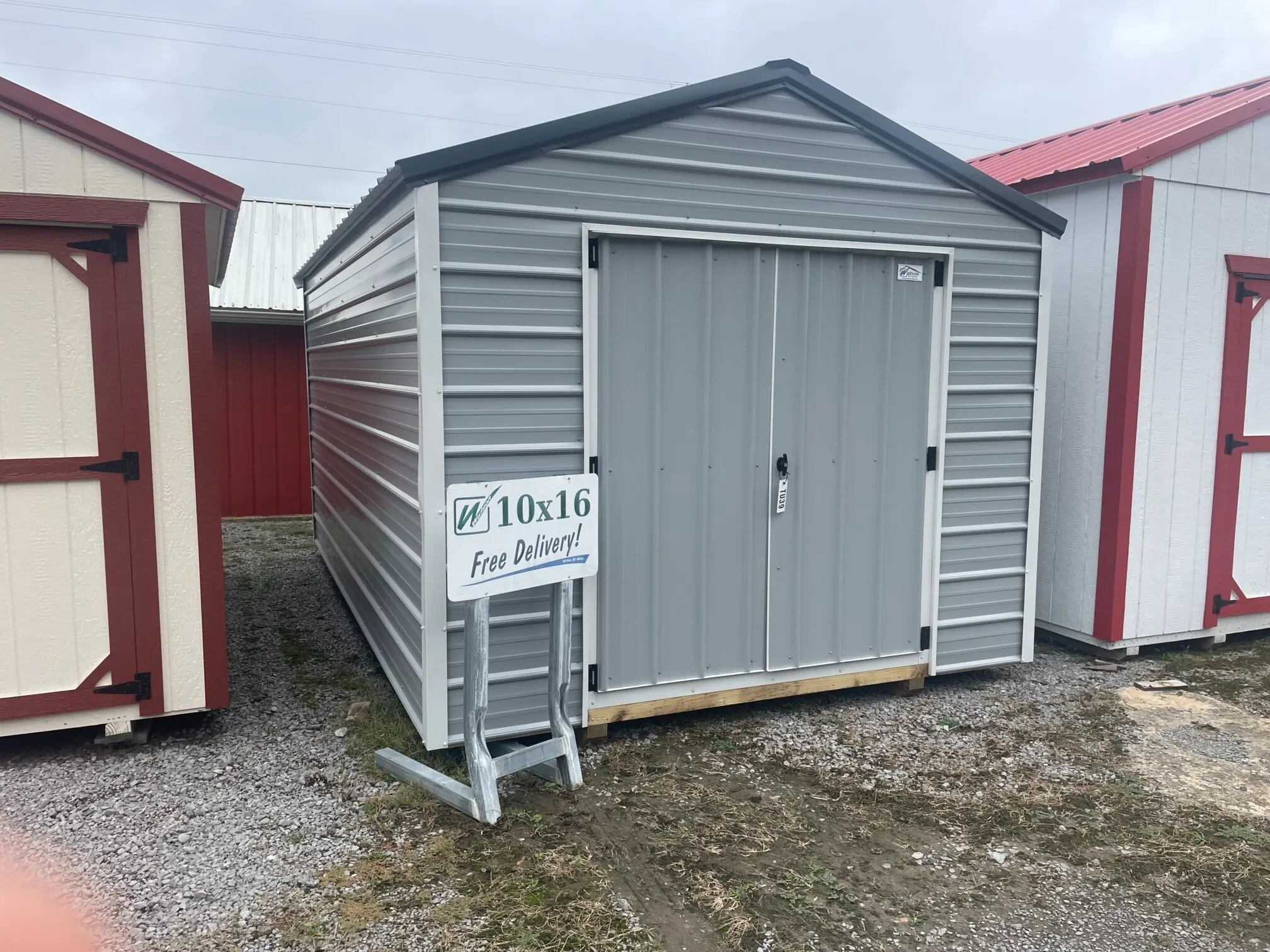 a light gray colored metal shed with horizontal siding metal and vertical metal on the double doors