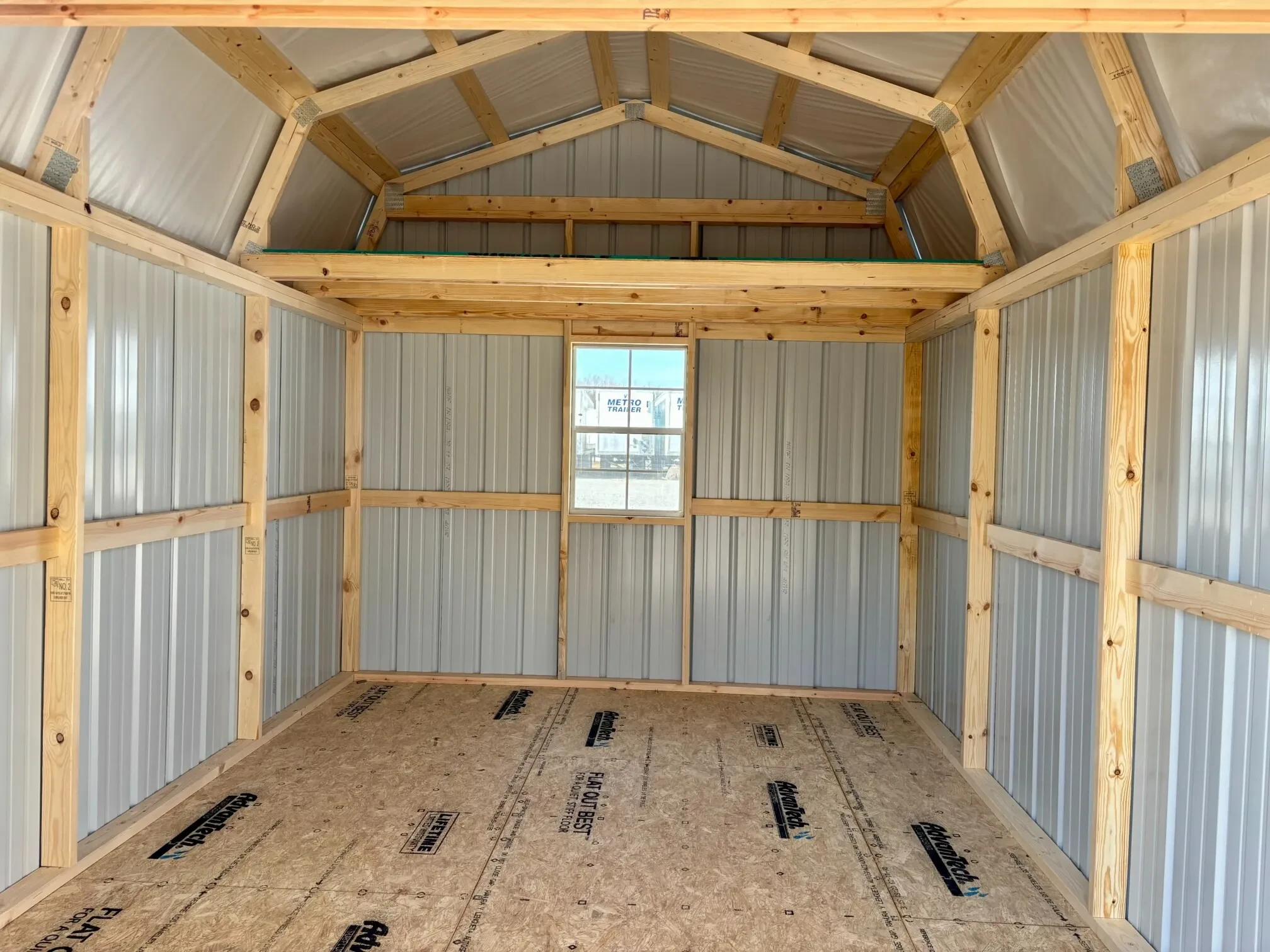 inside a metal lofted barn with a loft and a window along the back wall