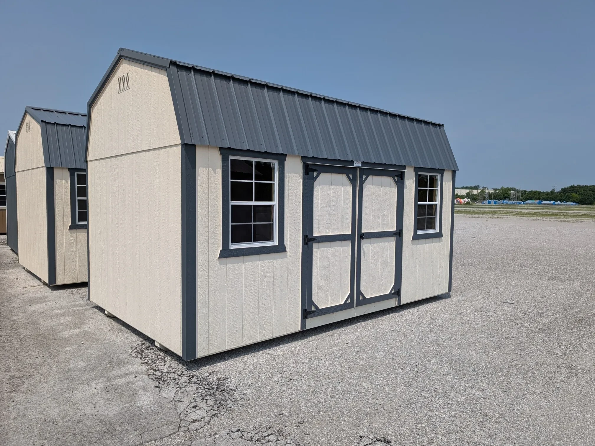 a white side lofted barn with double doors closed and two windows, one on each side of the double doors