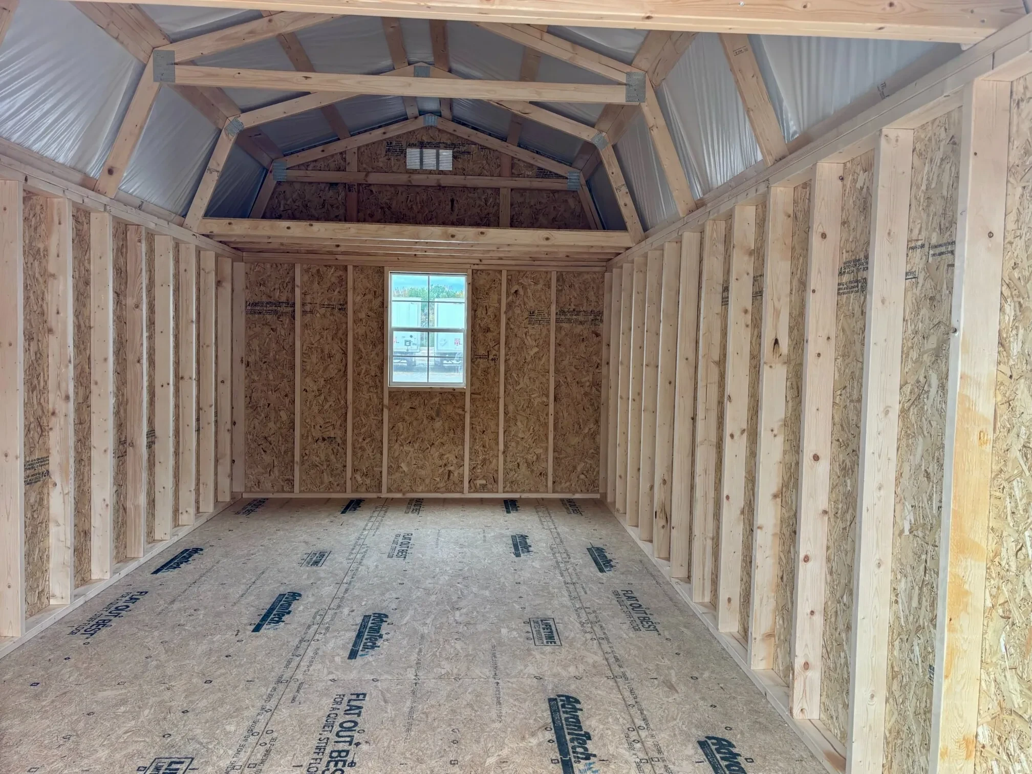 a window under a loft on the back wall inside a wood lofted barn
