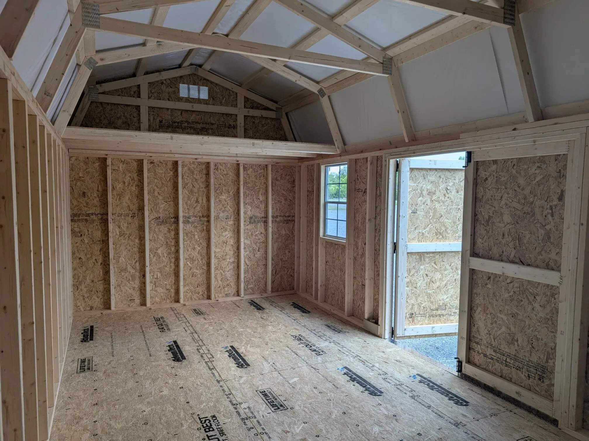 inside a wood lofted barn with a loft, a window, and double doors that are open