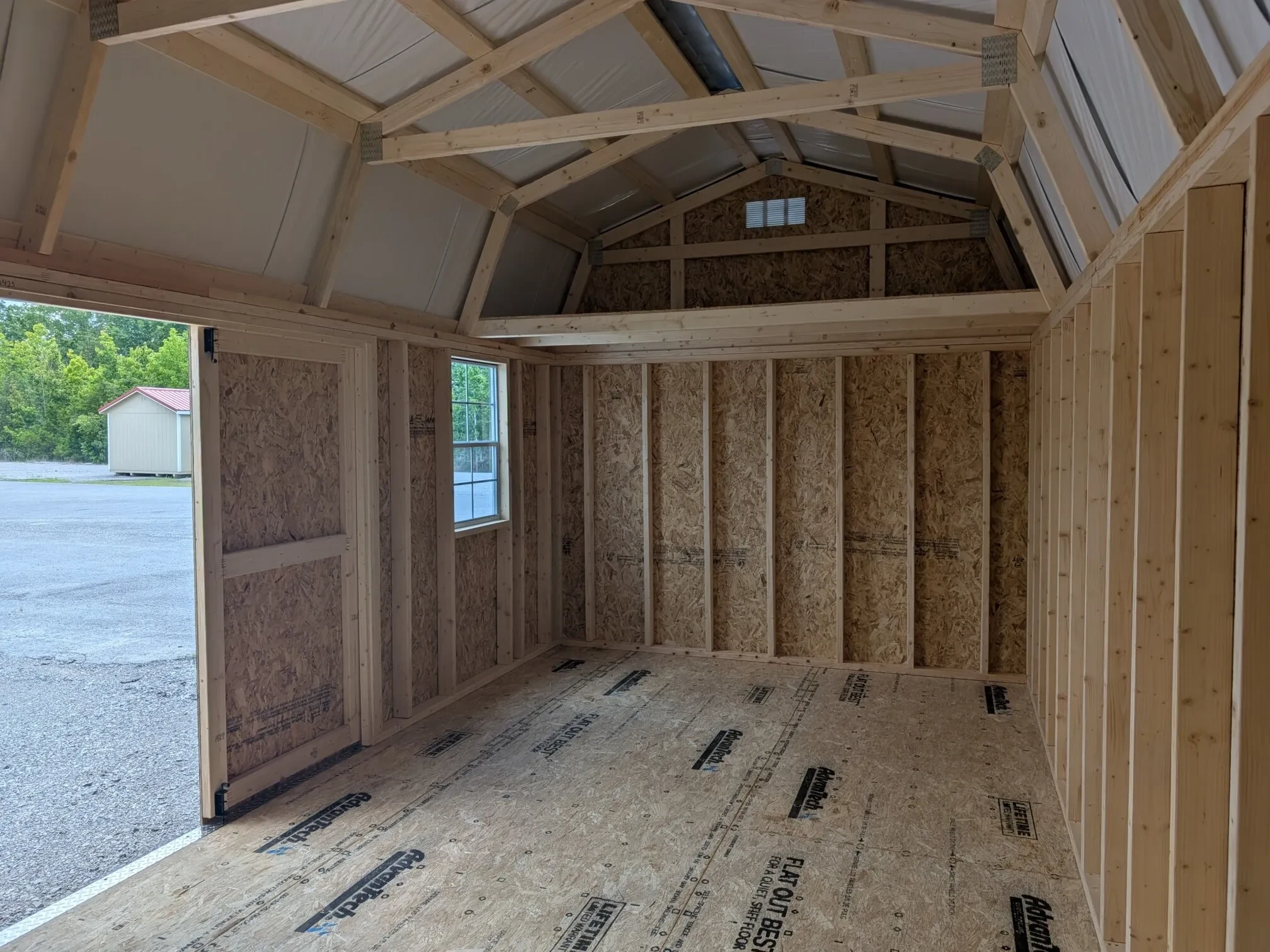looking at a loft, a window, and an open door from inside a wood side lofted barn