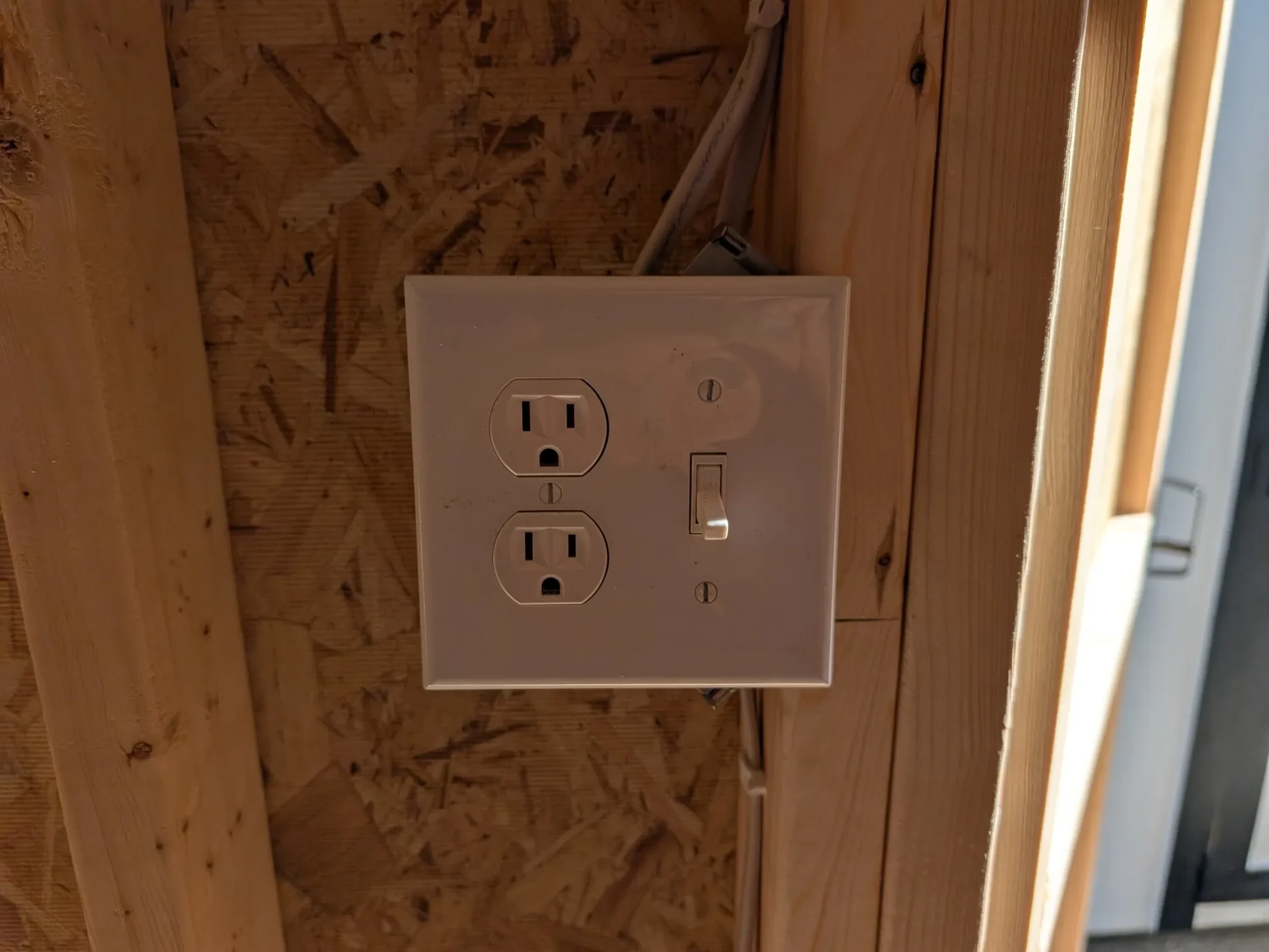 a receptacle and light switch combo inside a wood shed