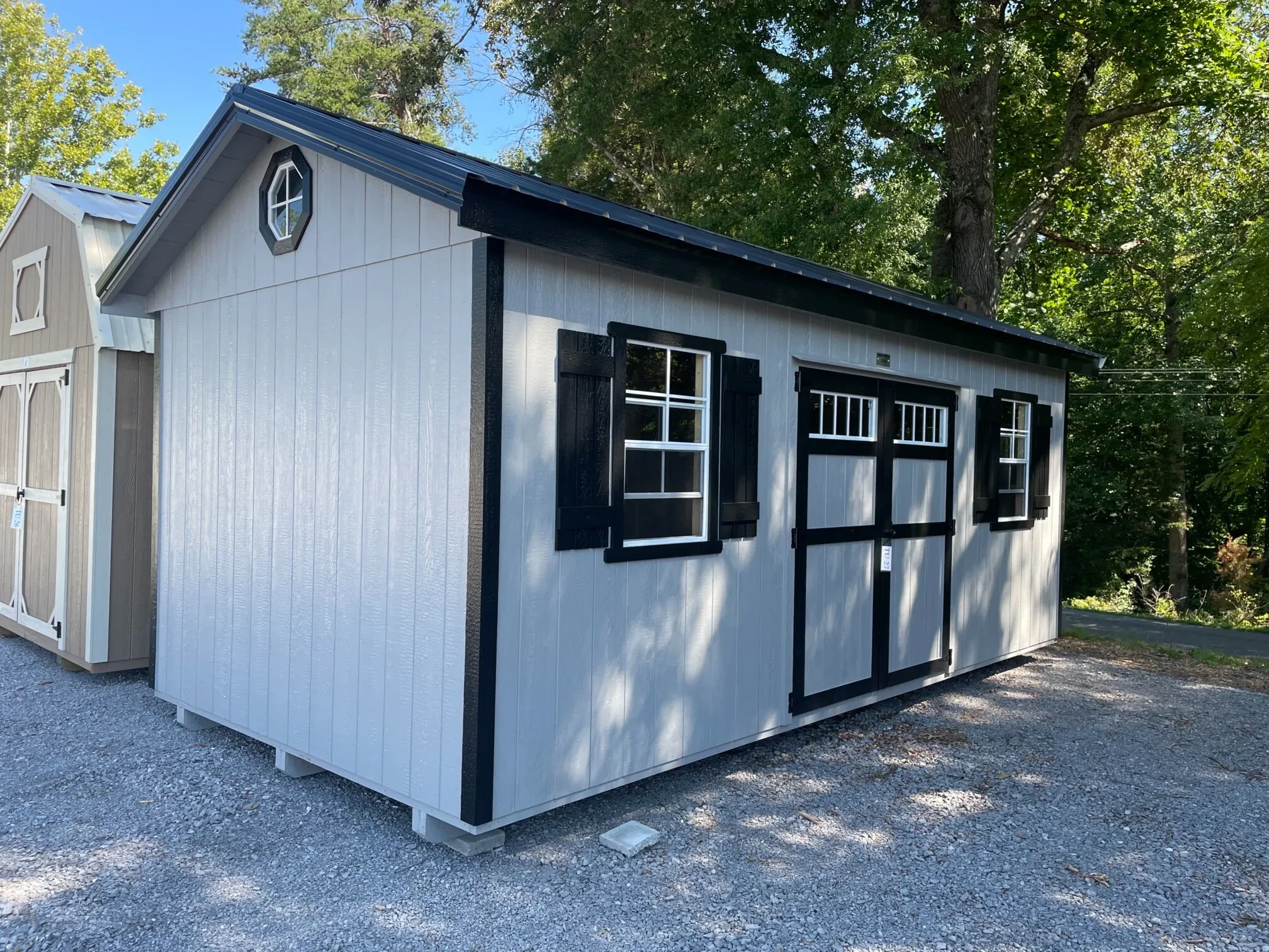 a light gray garden shed with double doors, multiple windows, and black shutters and roof