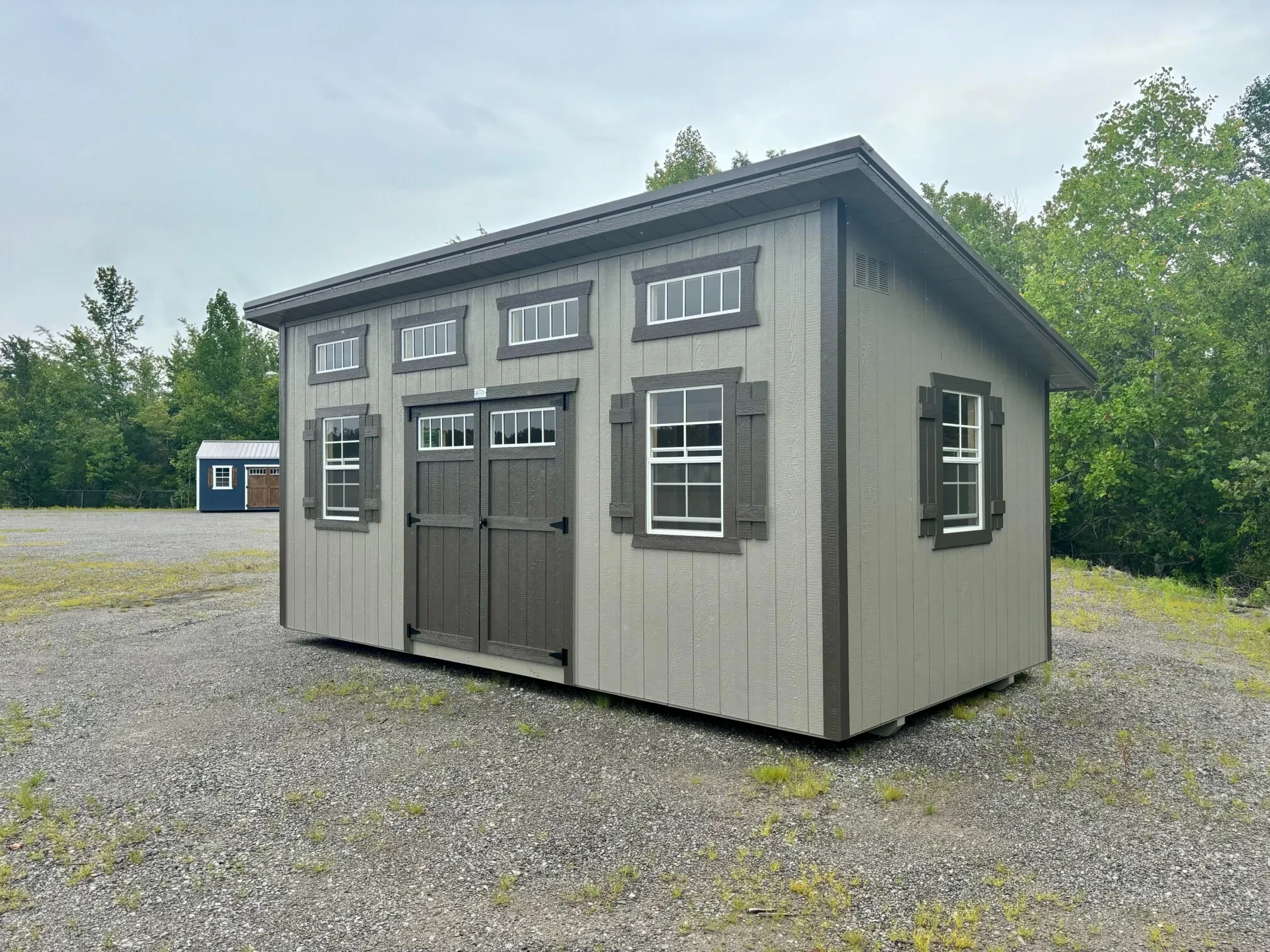 a studio shed with multiple vinyl insulated windows, transom windows, and shutter