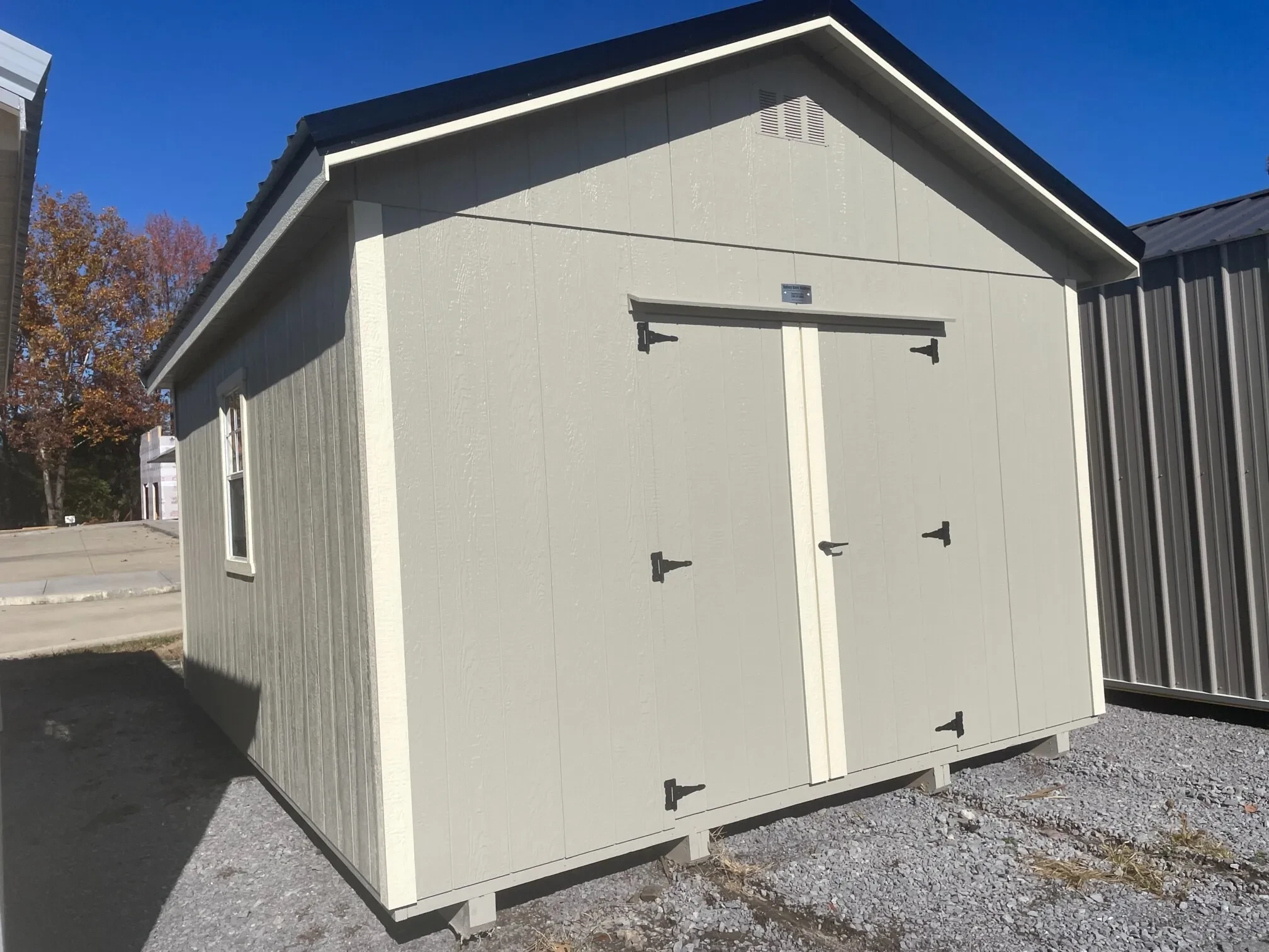 a wood utility shed with double doors and a window on the left and right wall