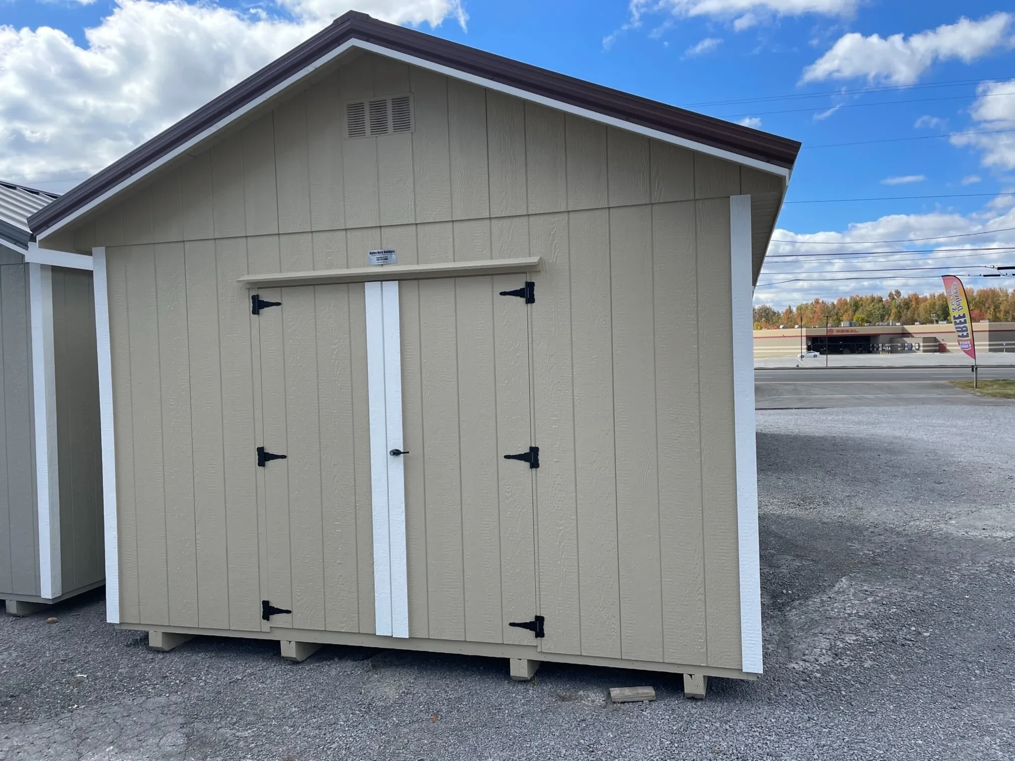 a premium wood shed with a roof overhang painted a light stone color with double doors