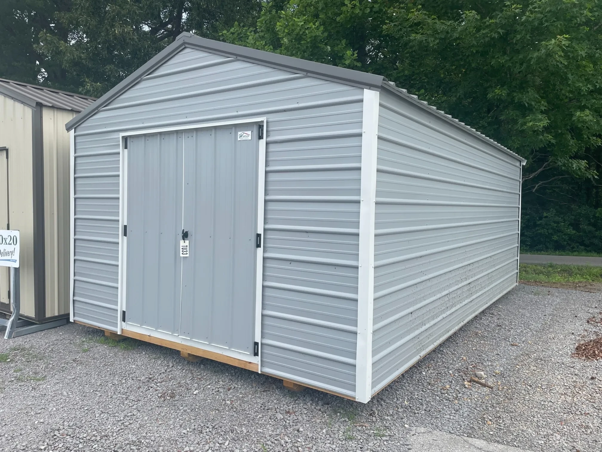 a large gray metal shed with white trim and double doors