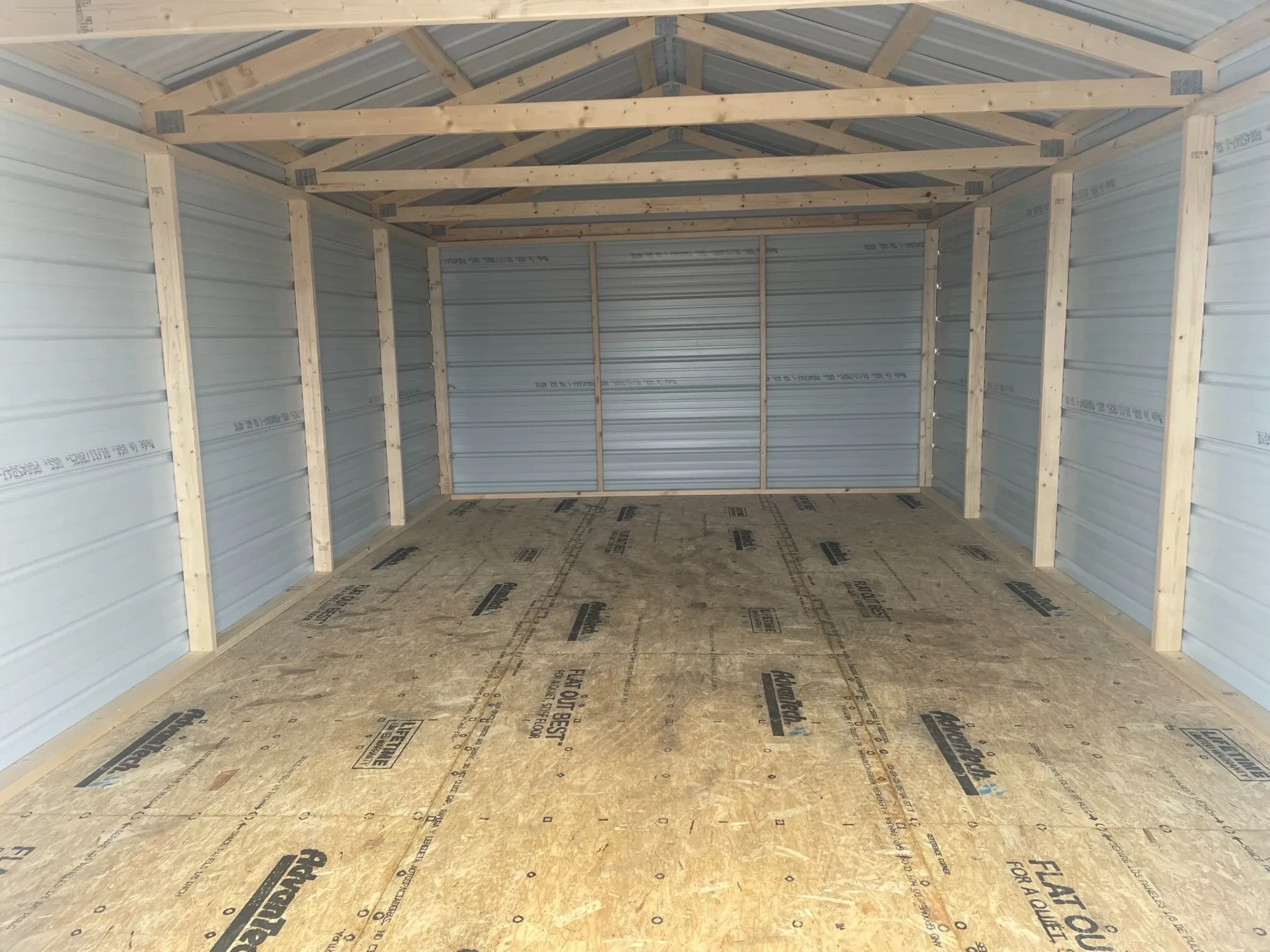 inside a large gray metal shed with lumber framing and a wood floor