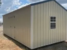 the back side of a stone colored garage showing double doors and a window on the back wall