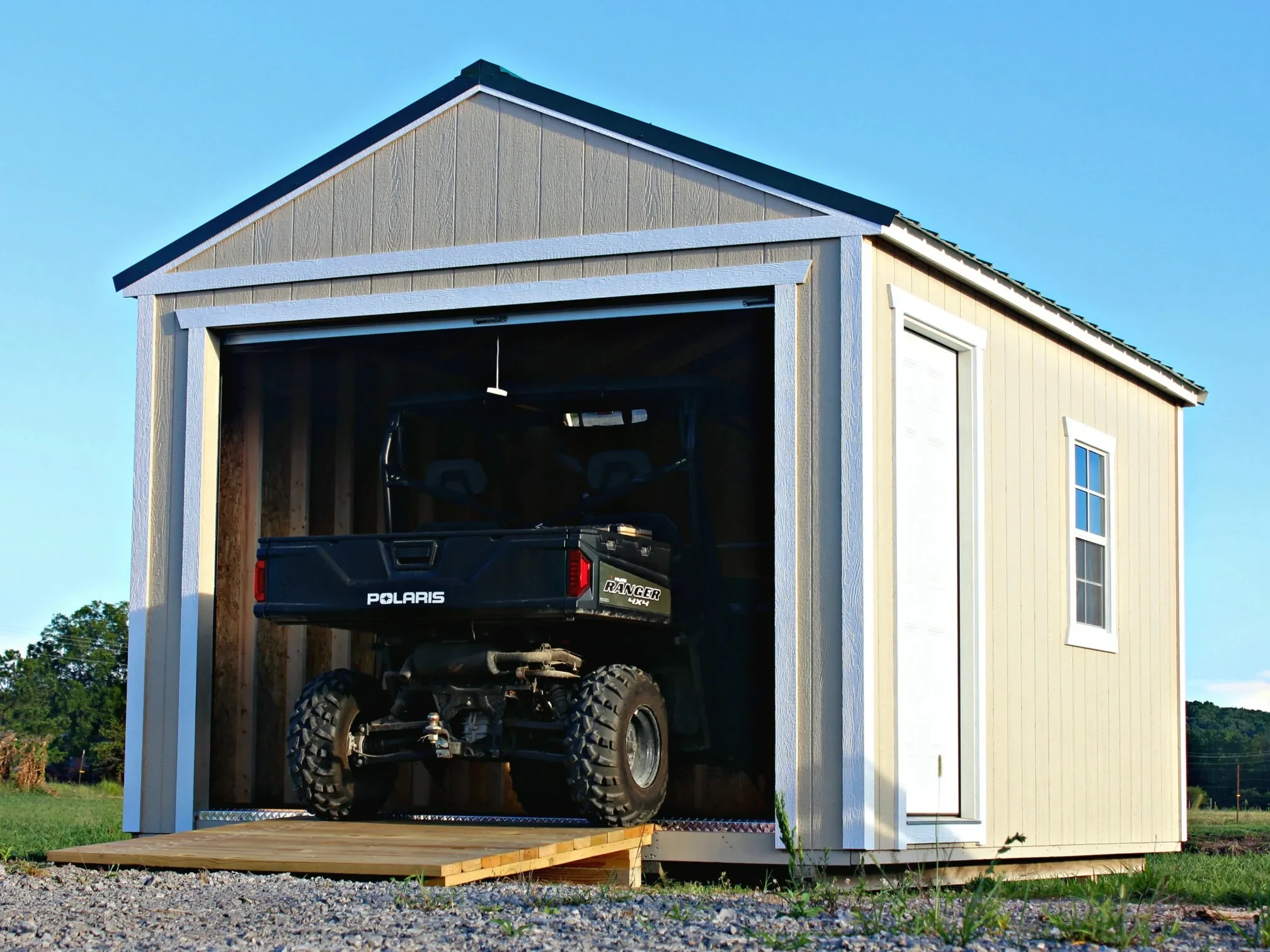 an atv parked in a shed with a garage door with the door open