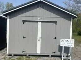 the front of a large gray shed with double doors and white trim