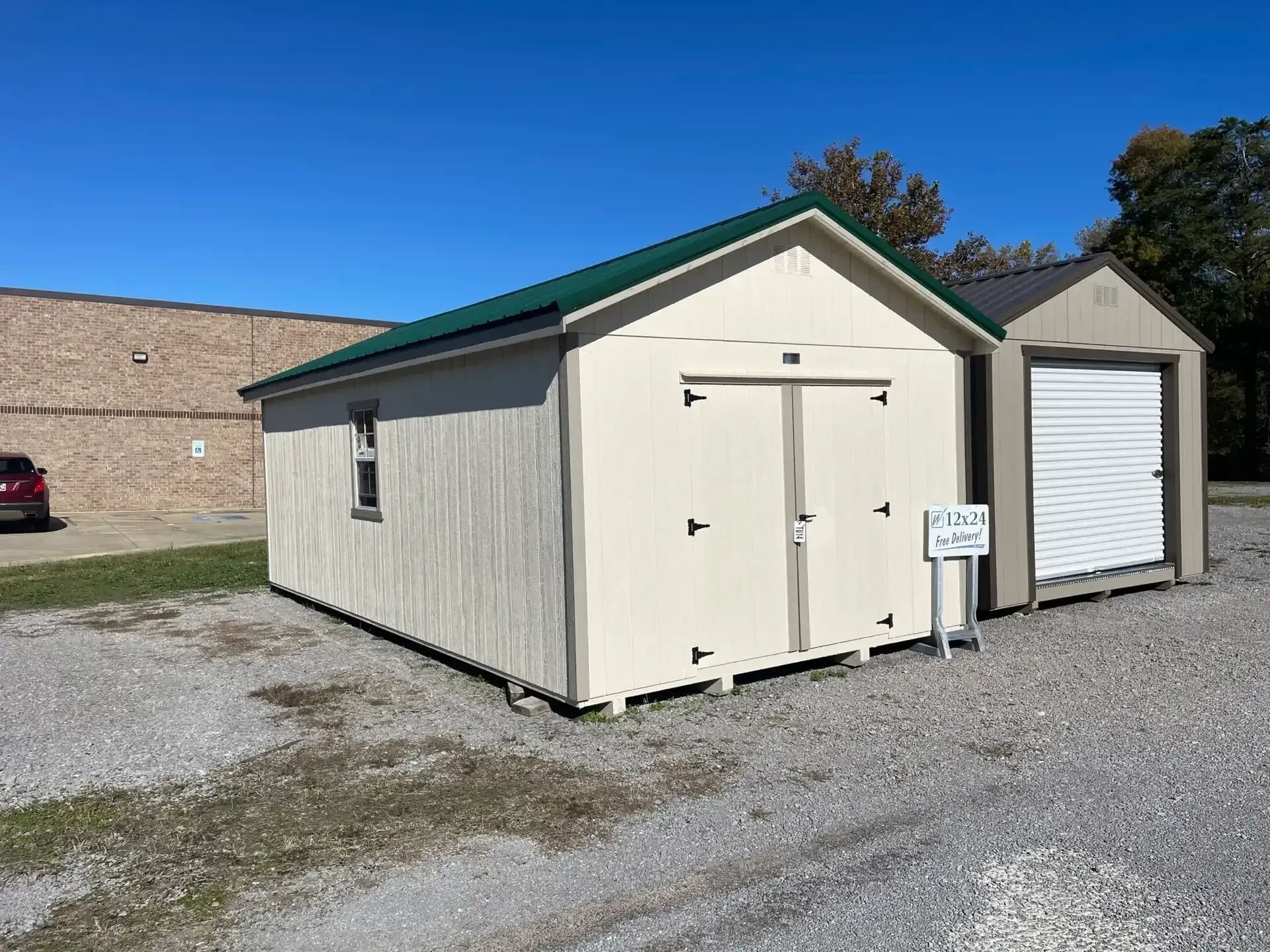 a large navajo white colored shed with a a green roof and a window