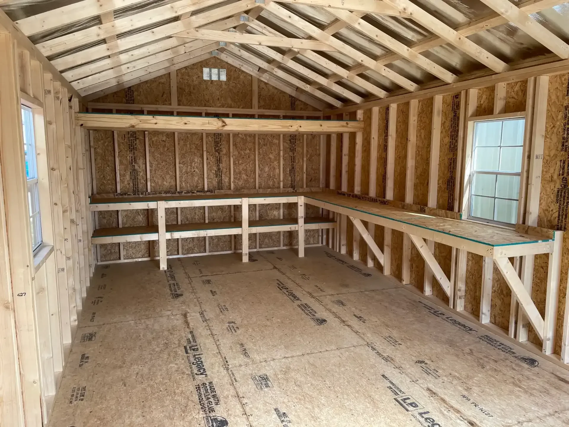 double shelves, a long work bench, and a loft along the back wall of a large wood shed