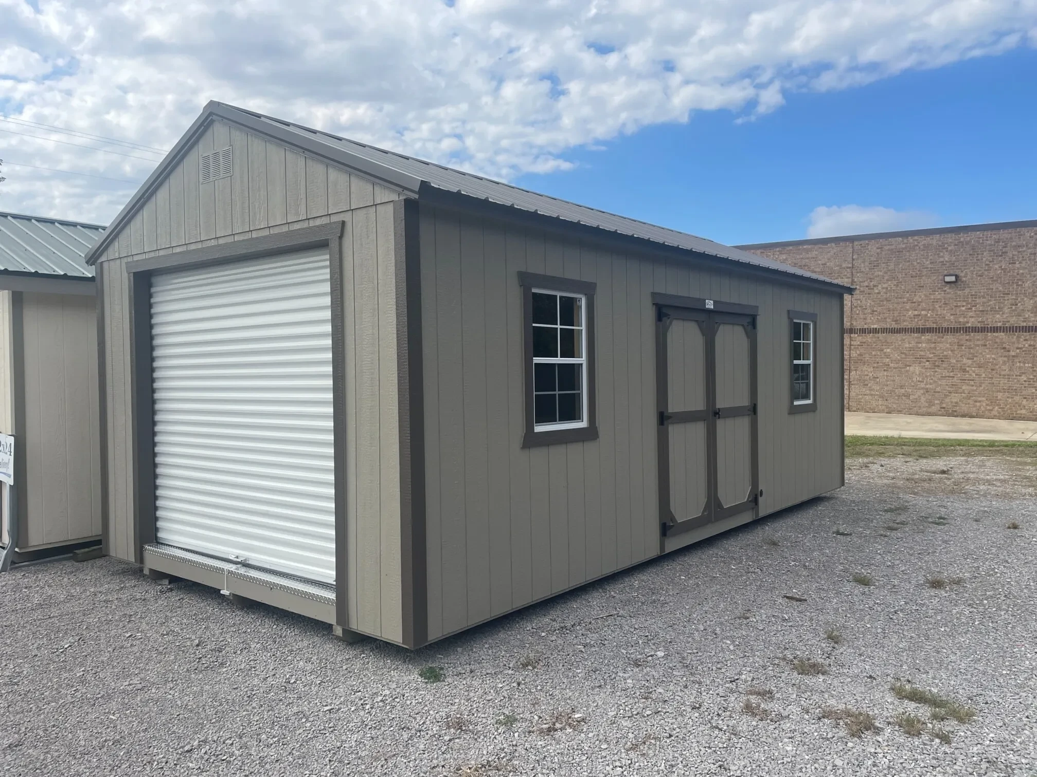 a wood garage shed with a rollup door in the front and double doors and windows on the right side