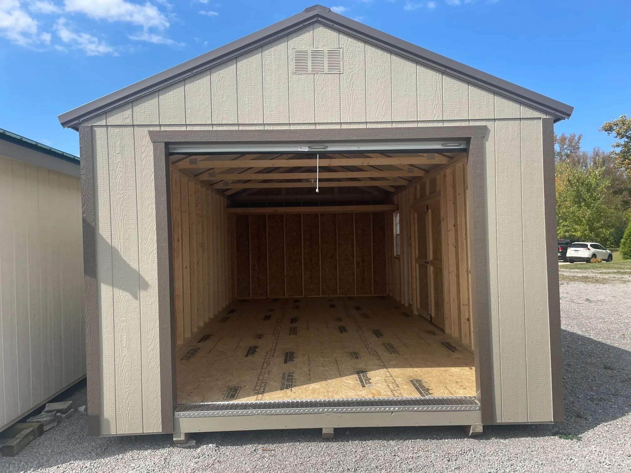 looking through the open rollup garage door into a wood garage shed