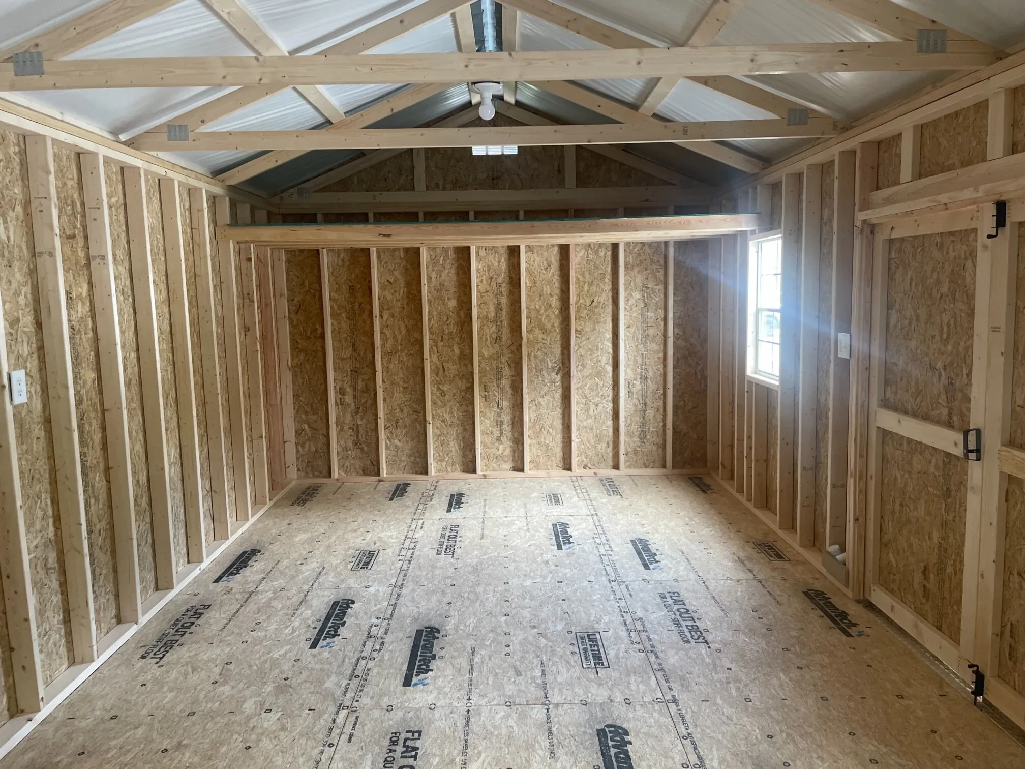 inside a large garage shed that has a loft and a window with the sun shining through the window