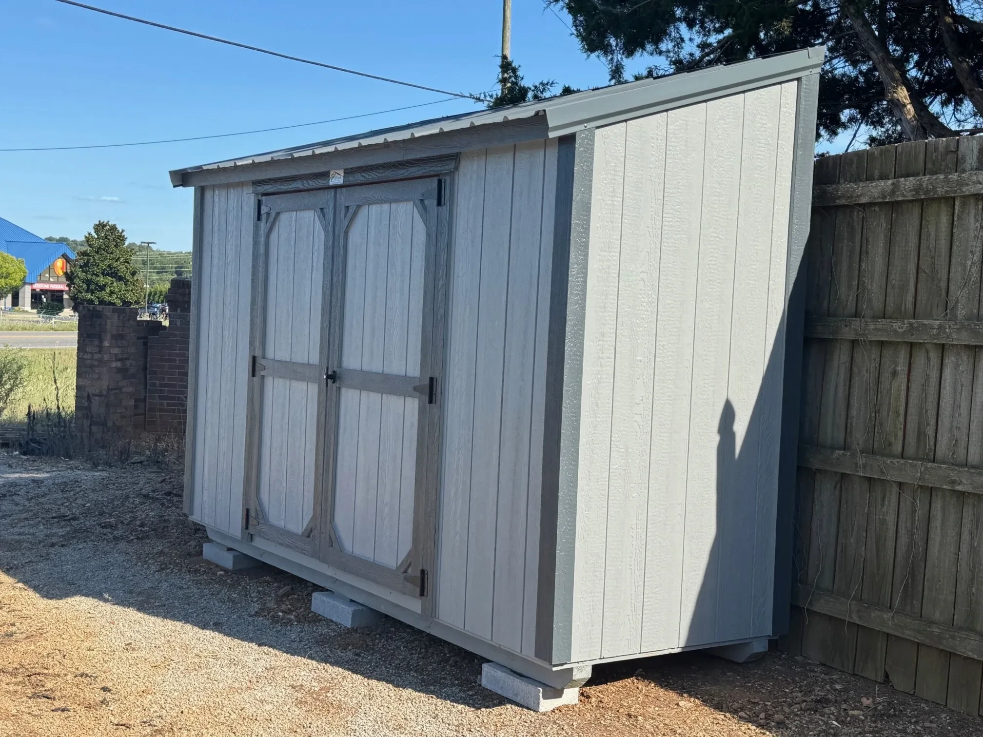 a small leanto style shed up against a wood picket fence