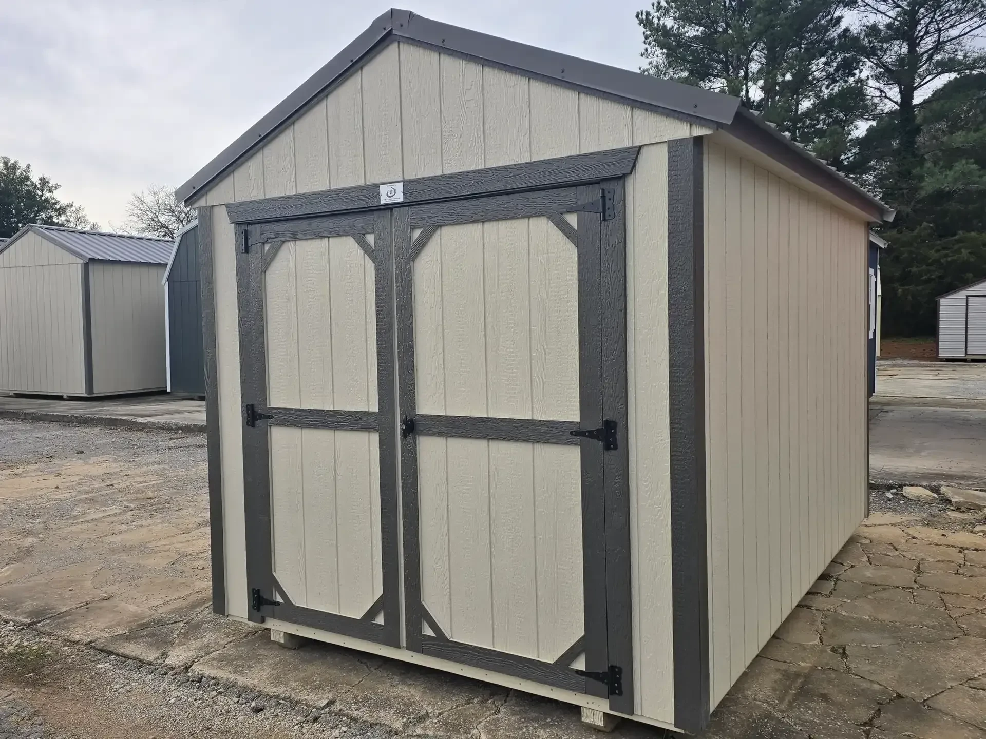 a wood utility shed painted a light stone color with double doors