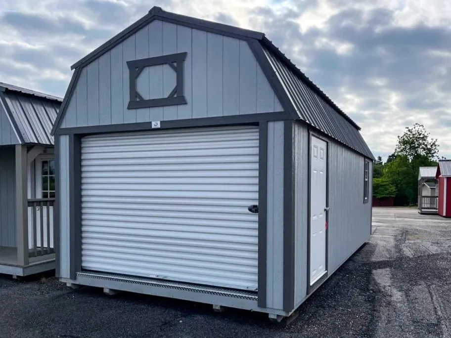 a lofted garage with a garage door in the end and a walk-in door and window in the side