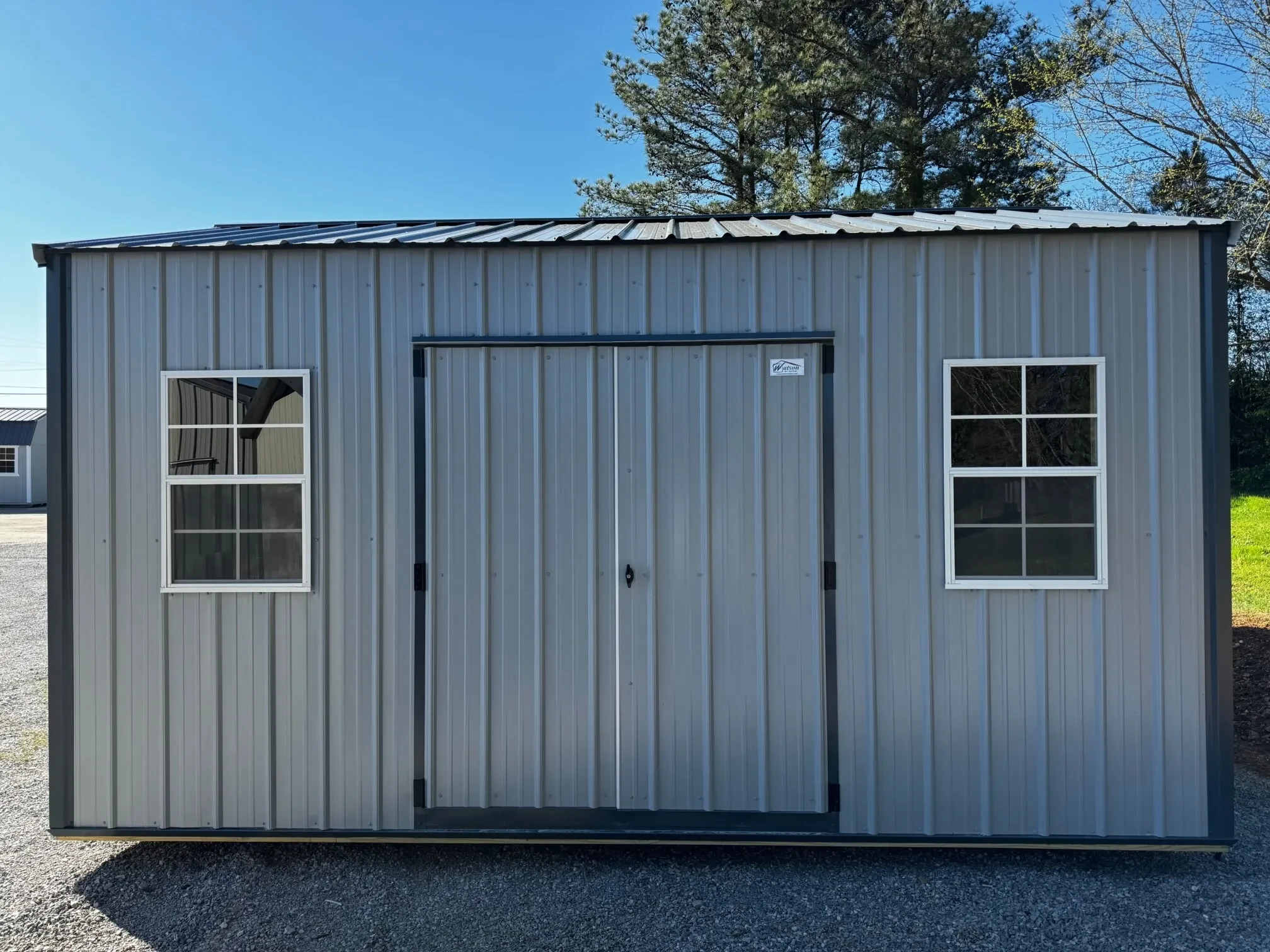 a gray metal garden shed with double doors and two windows