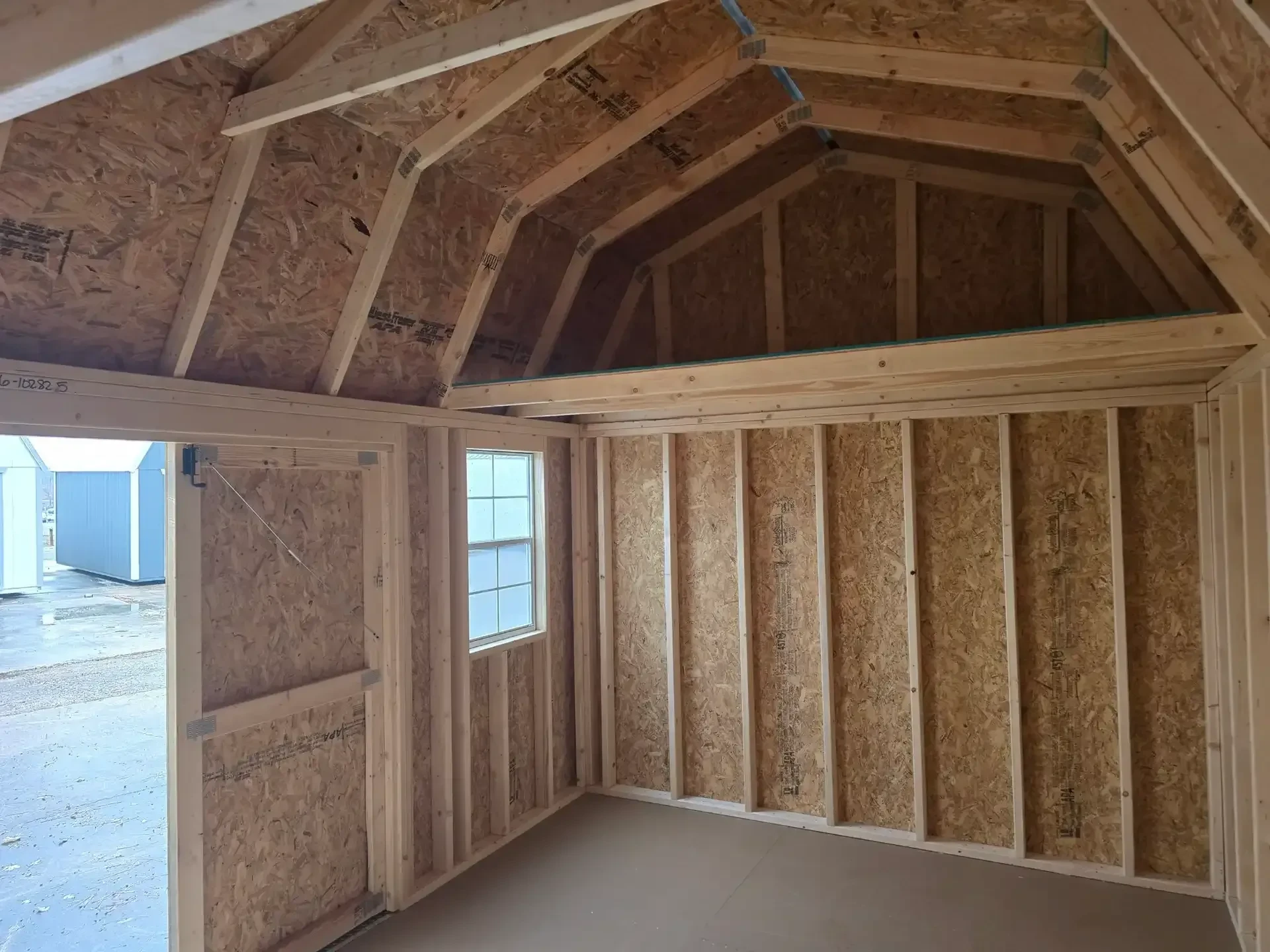 inside a side lofted barn showing a loft and a window and one of the double doors open
